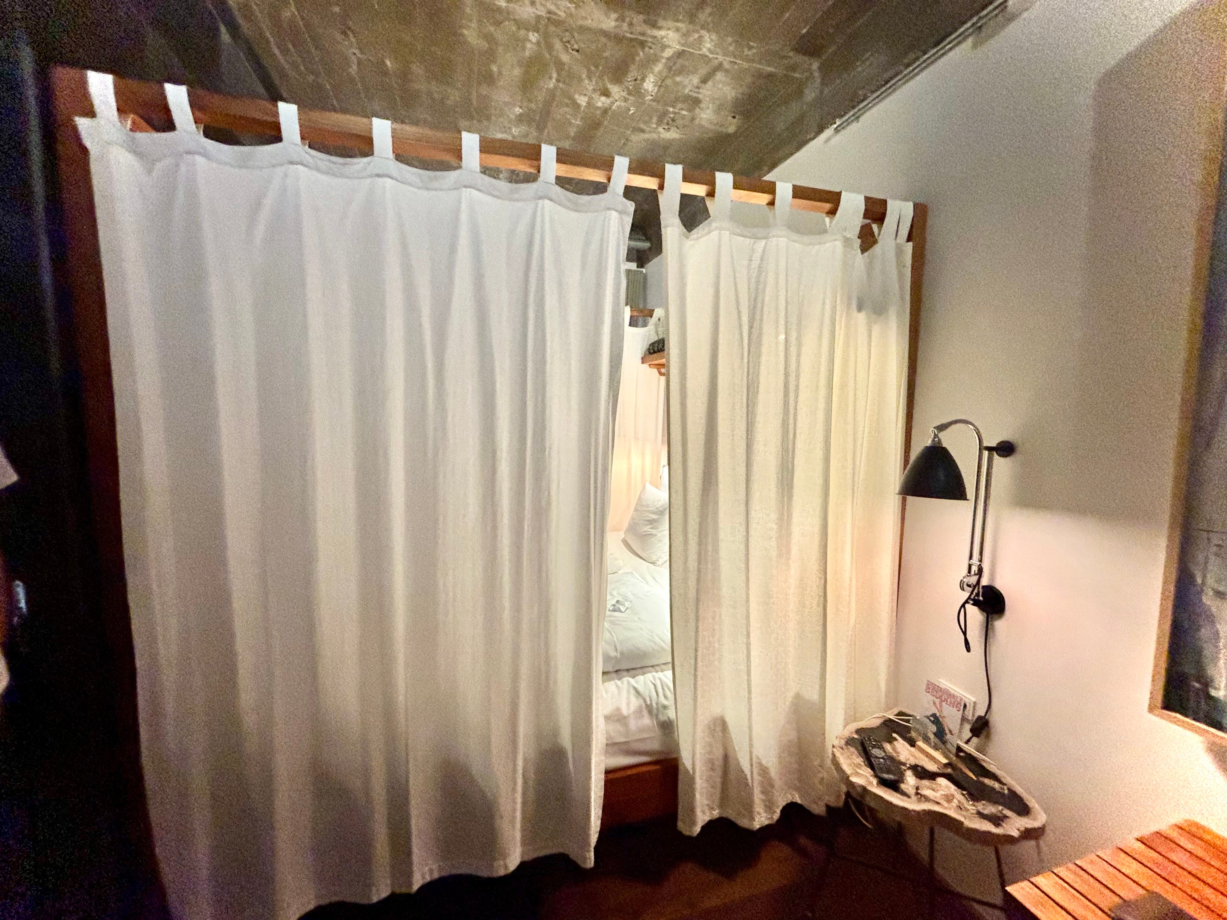A canopy bed with curtains mostly closed.