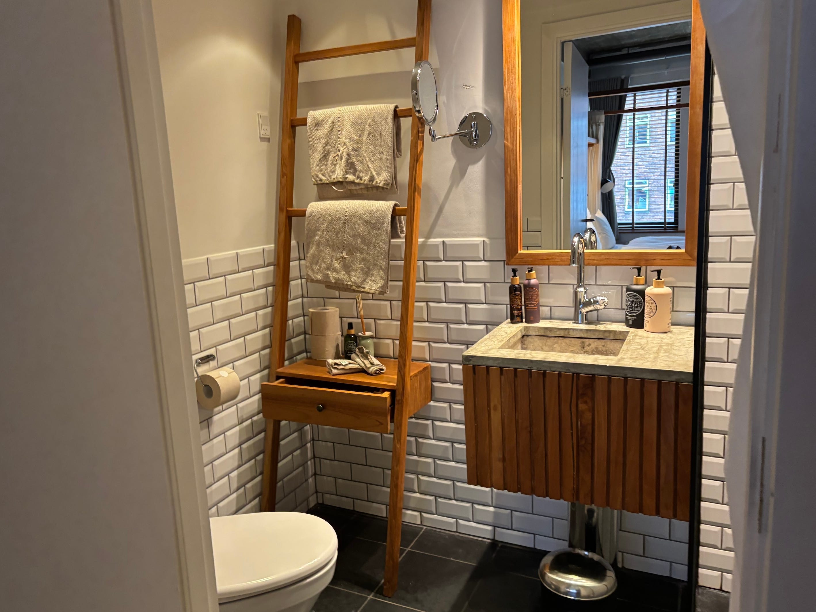 A bathroom with a vanity and a free-standing wooden shelf.