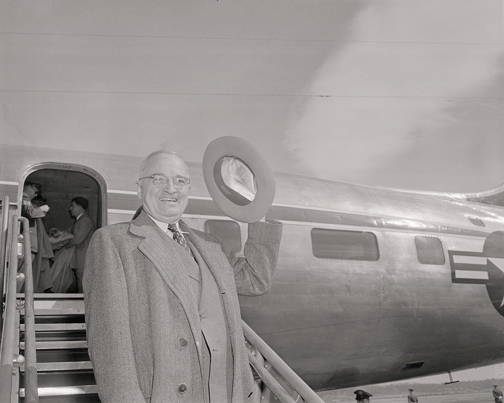 Harry Truman waves on the steps of his plane, The Independence.