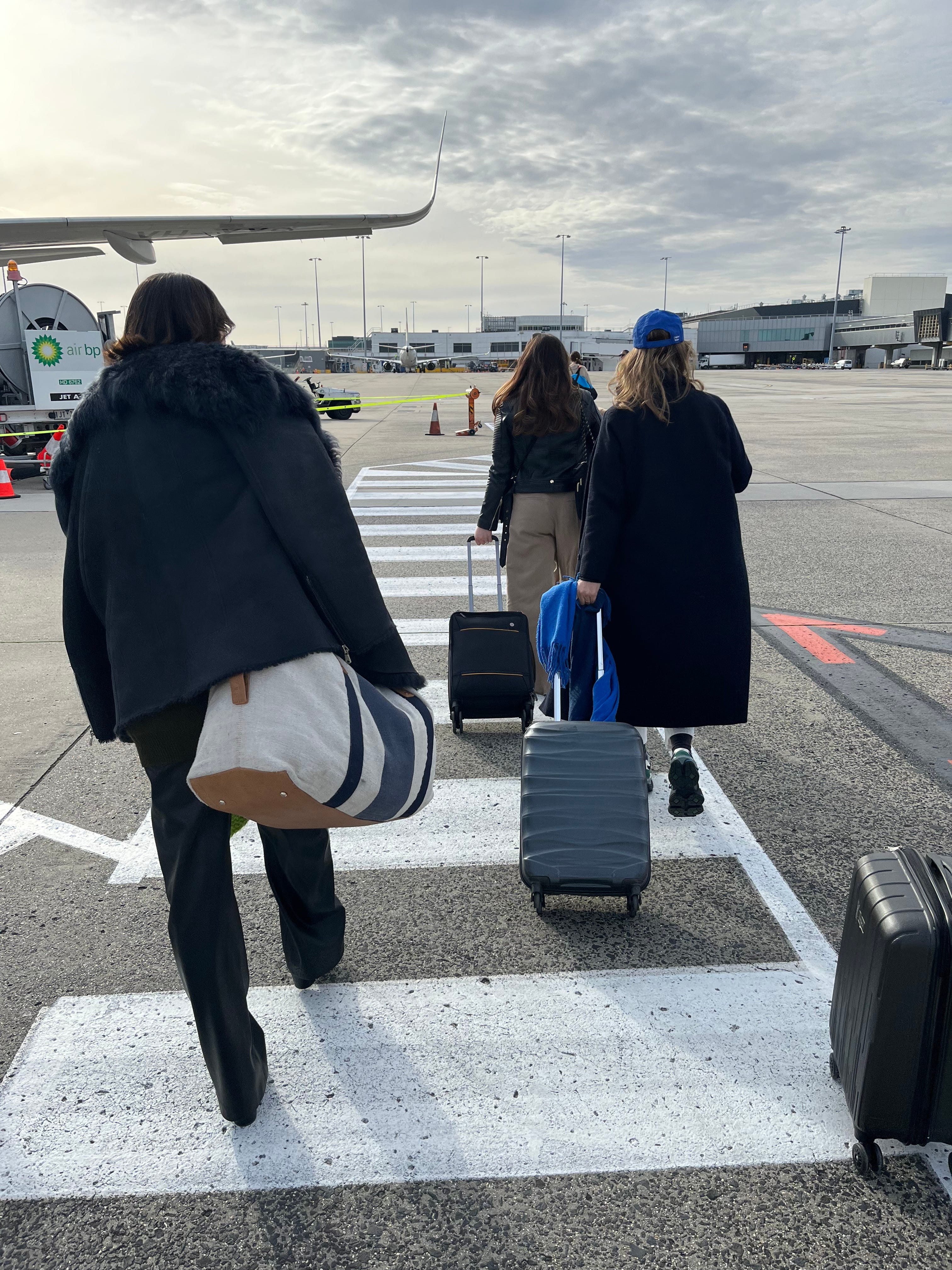 Members of a friend group board a plane to take a group vacation together.