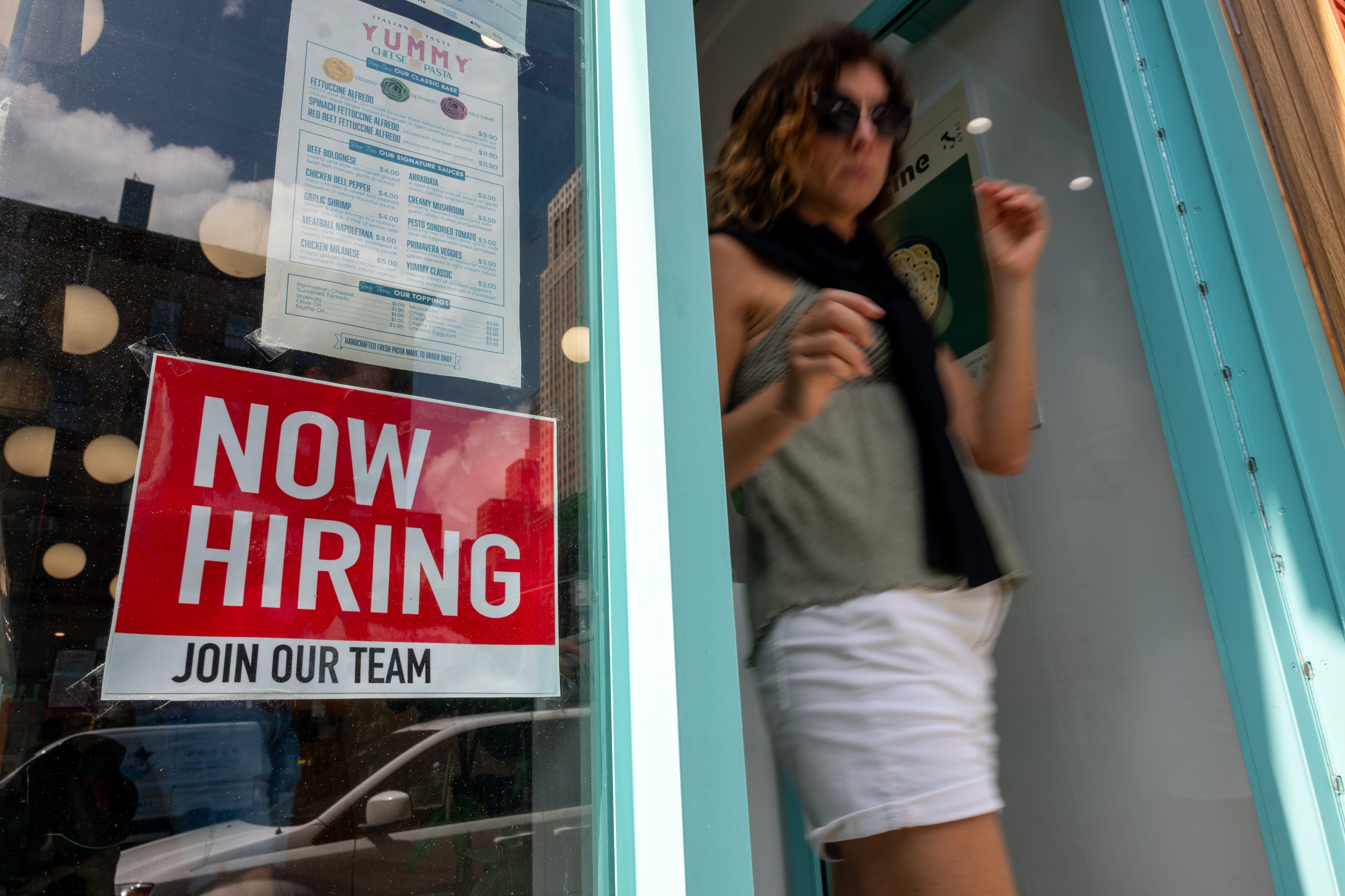A 'now hiring' sign on a business window