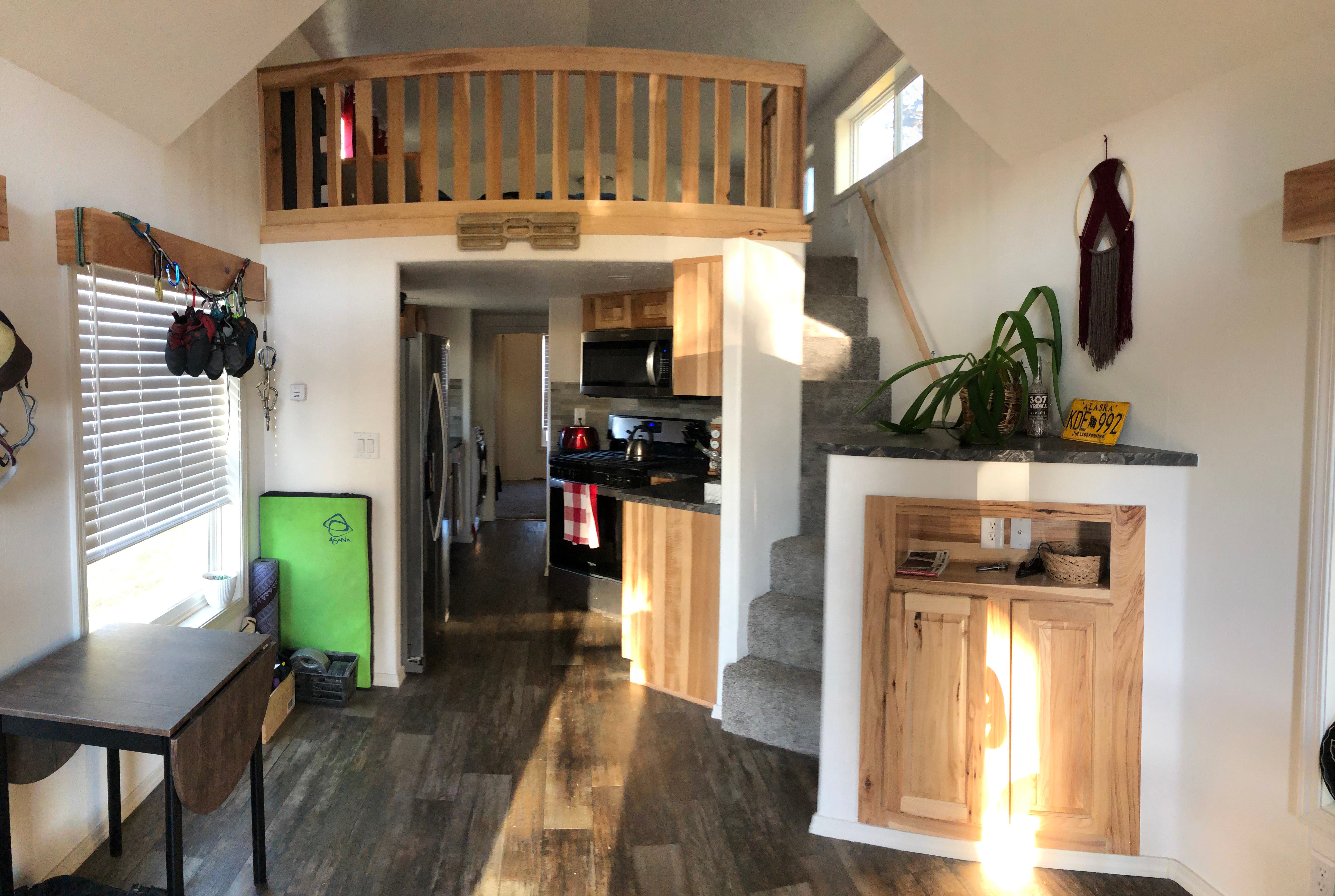 Small wood railing loft area above living area in tiny home