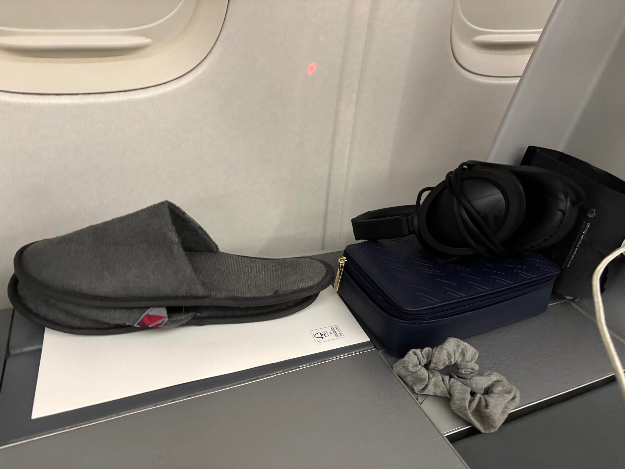 Slippers, a kit, headphones, and a scrunchii on a tray table.