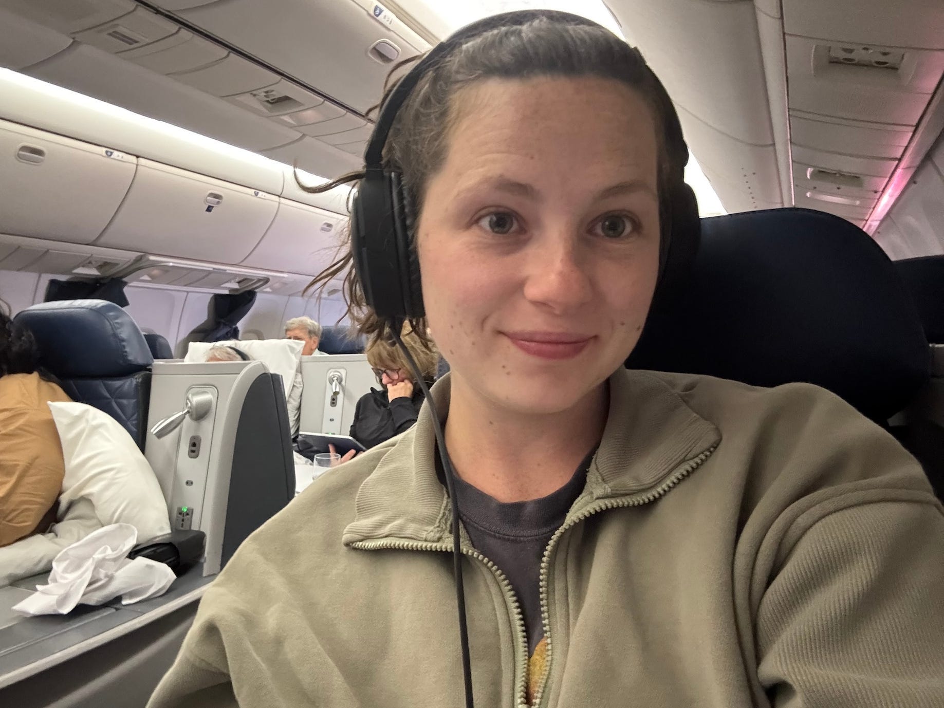 A selfie of a woman on a plane wearing headphones.