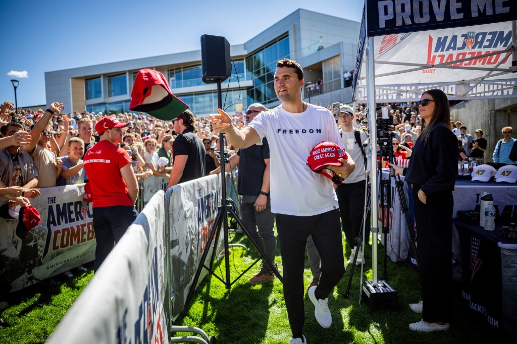 Charlie Kirk throws hats to the crowd.