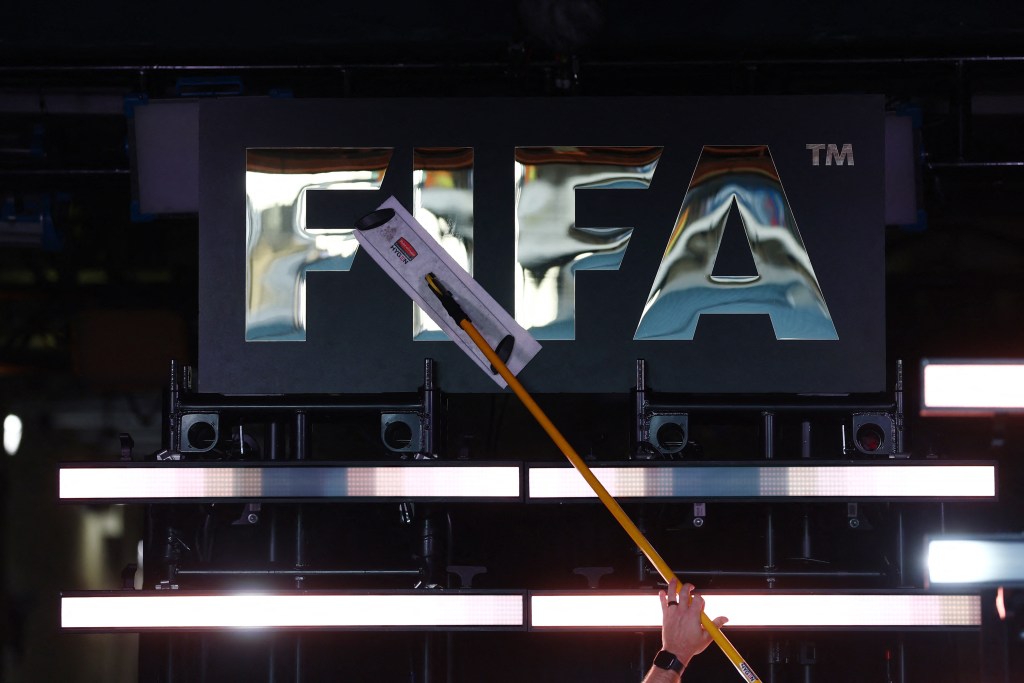 A person cleaning a large FIFA logo.
