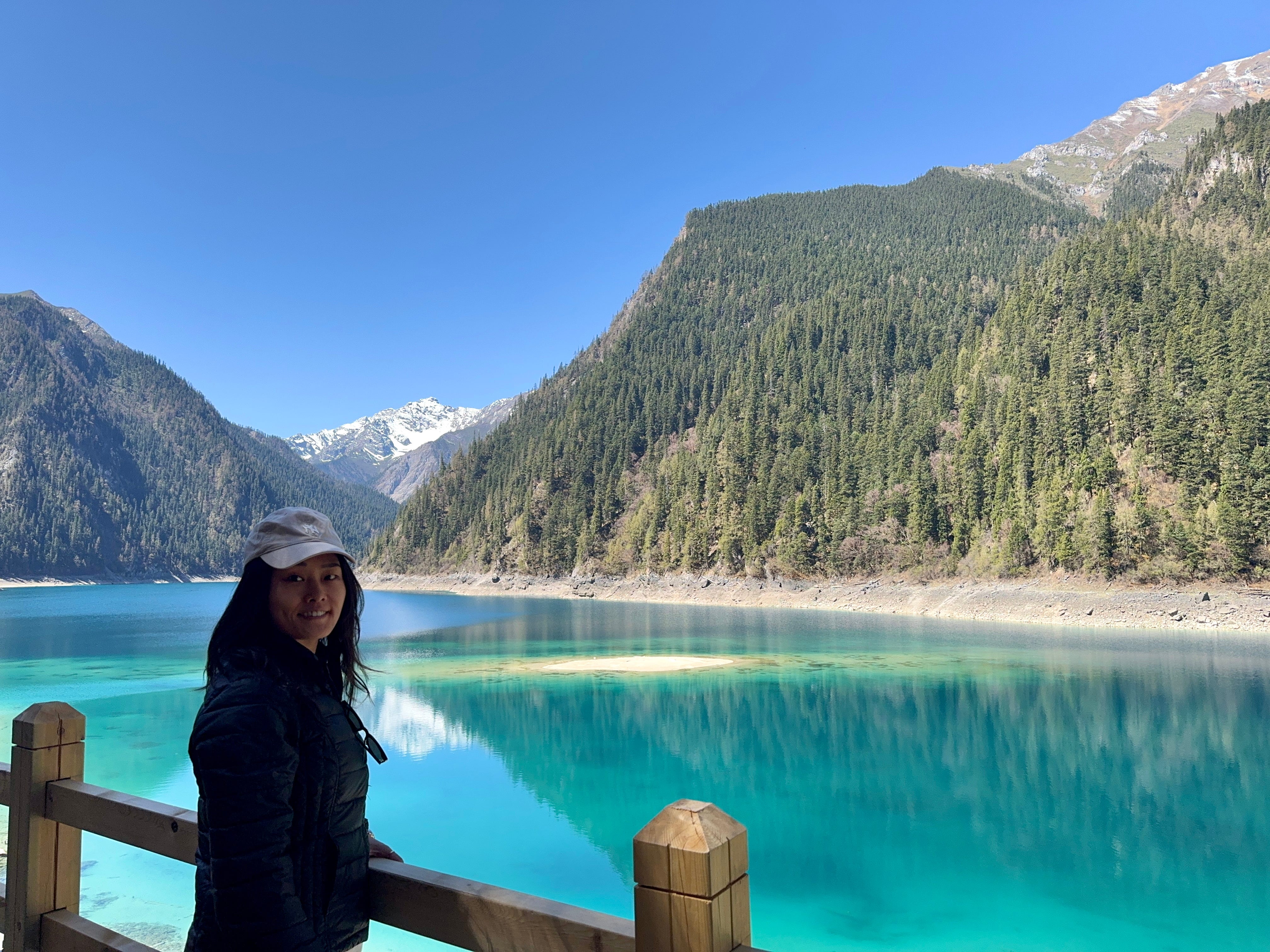 Yangyang Guo is standing by a bright blue lake while visiting Jiuzhaigou, China.