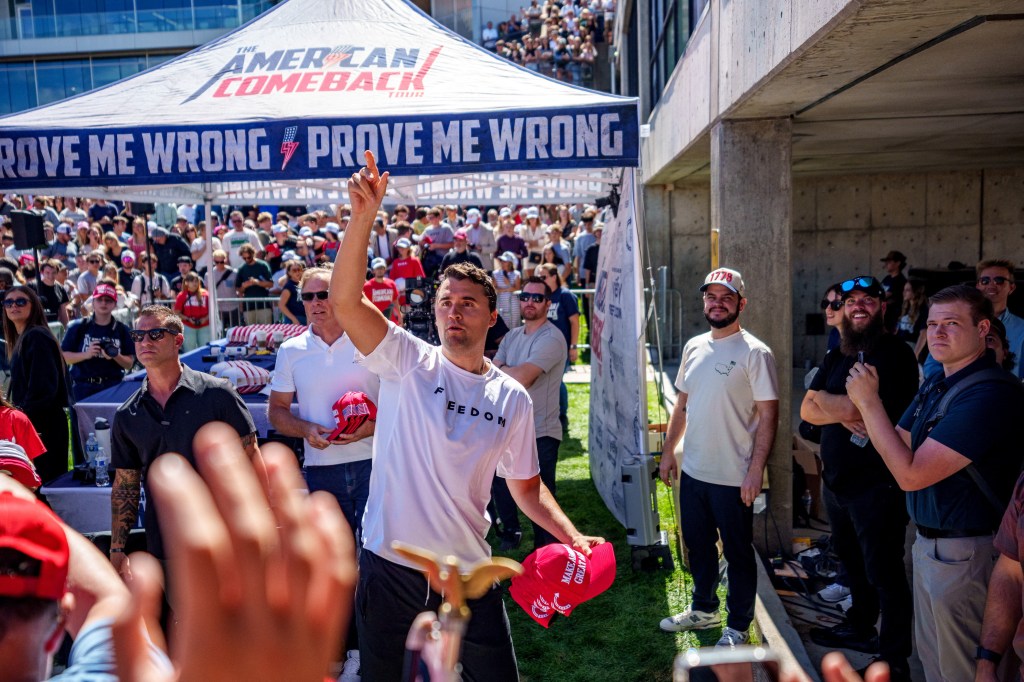 Charlie Kirk throwing hats to a crowd at a speaking event.