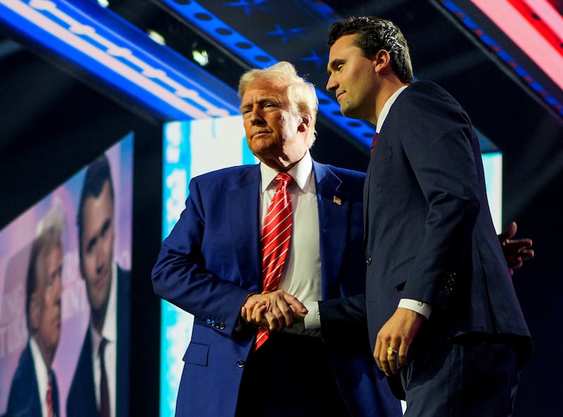 Donald Trump shakes hands with Turning Point USA founder Charlie Kirk, at Turning Point USA's AmericaFest in Phoenix, Arizona, U.S., December 22, 2024