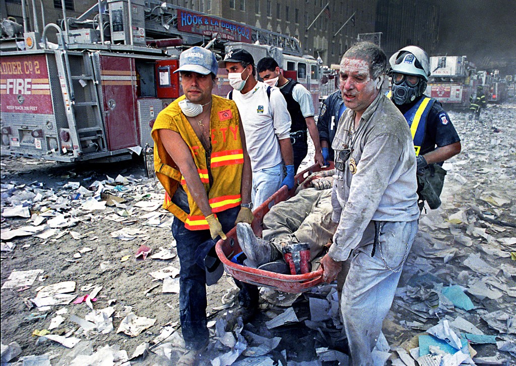 Rescue workers carrying an injured person on a stretcher amidst debris from the World Trade Center attacks.