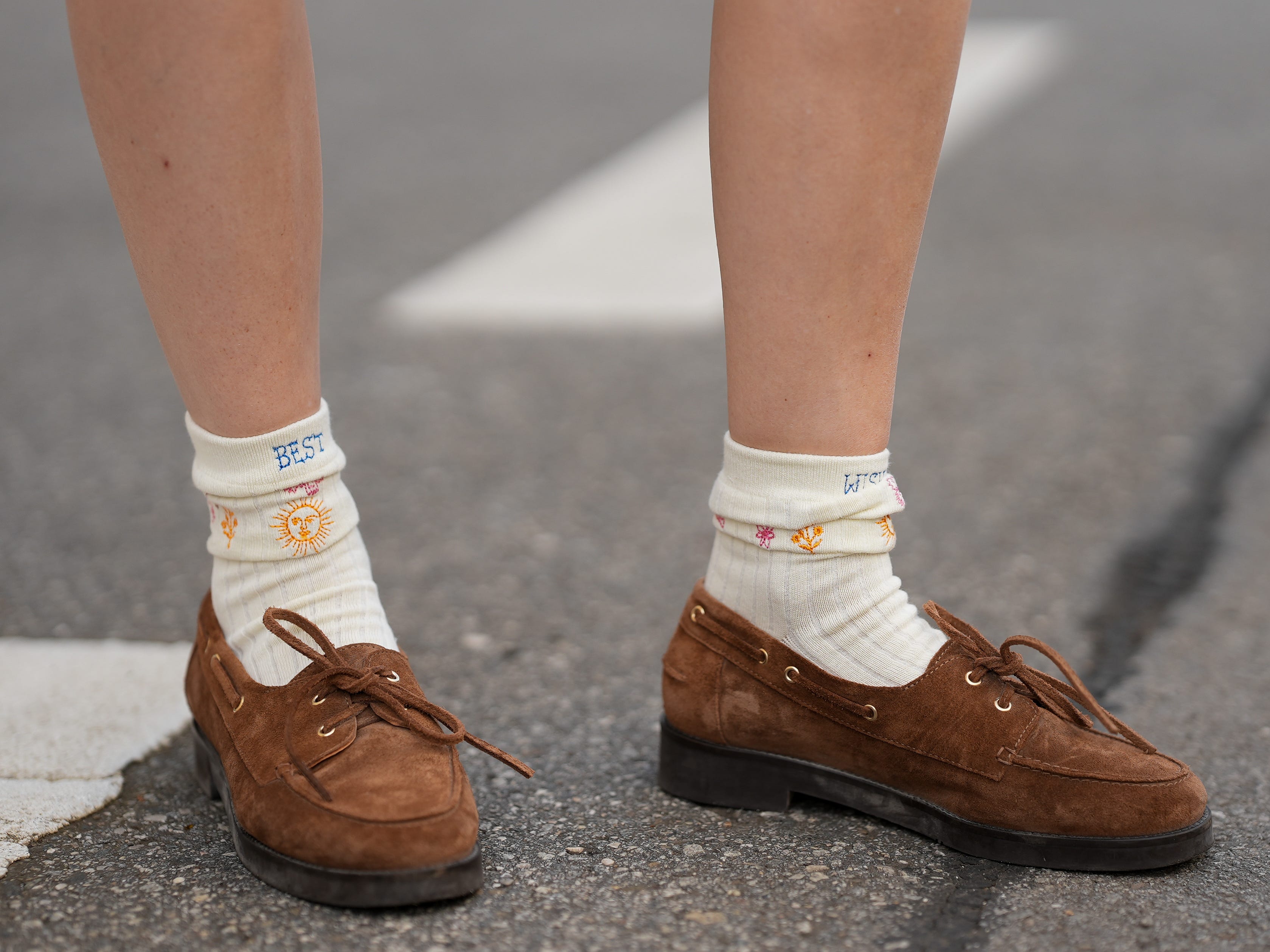 A person wearing suede boat shoes with ankle socks.