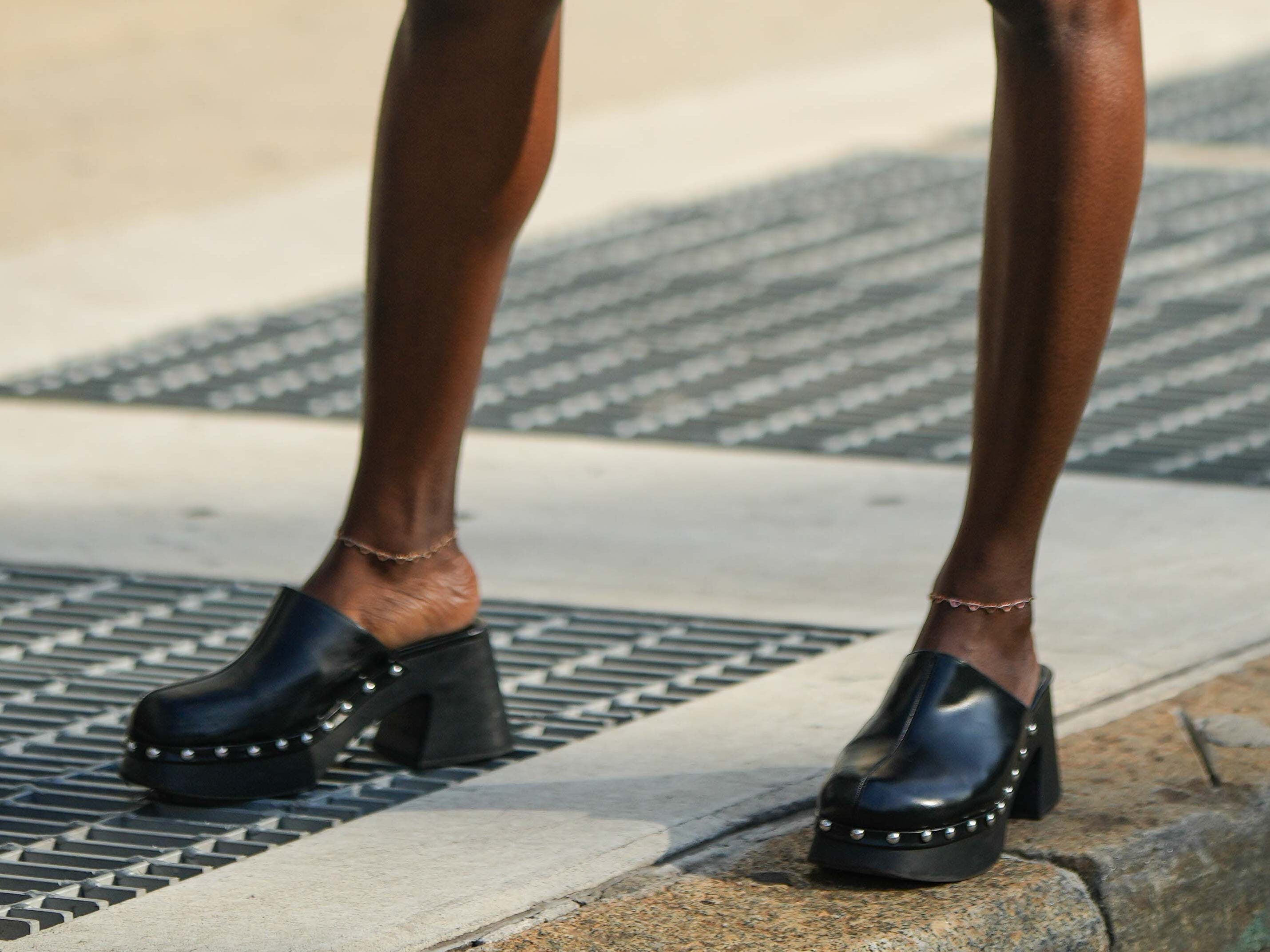A woman wearing a pair of black clogs.