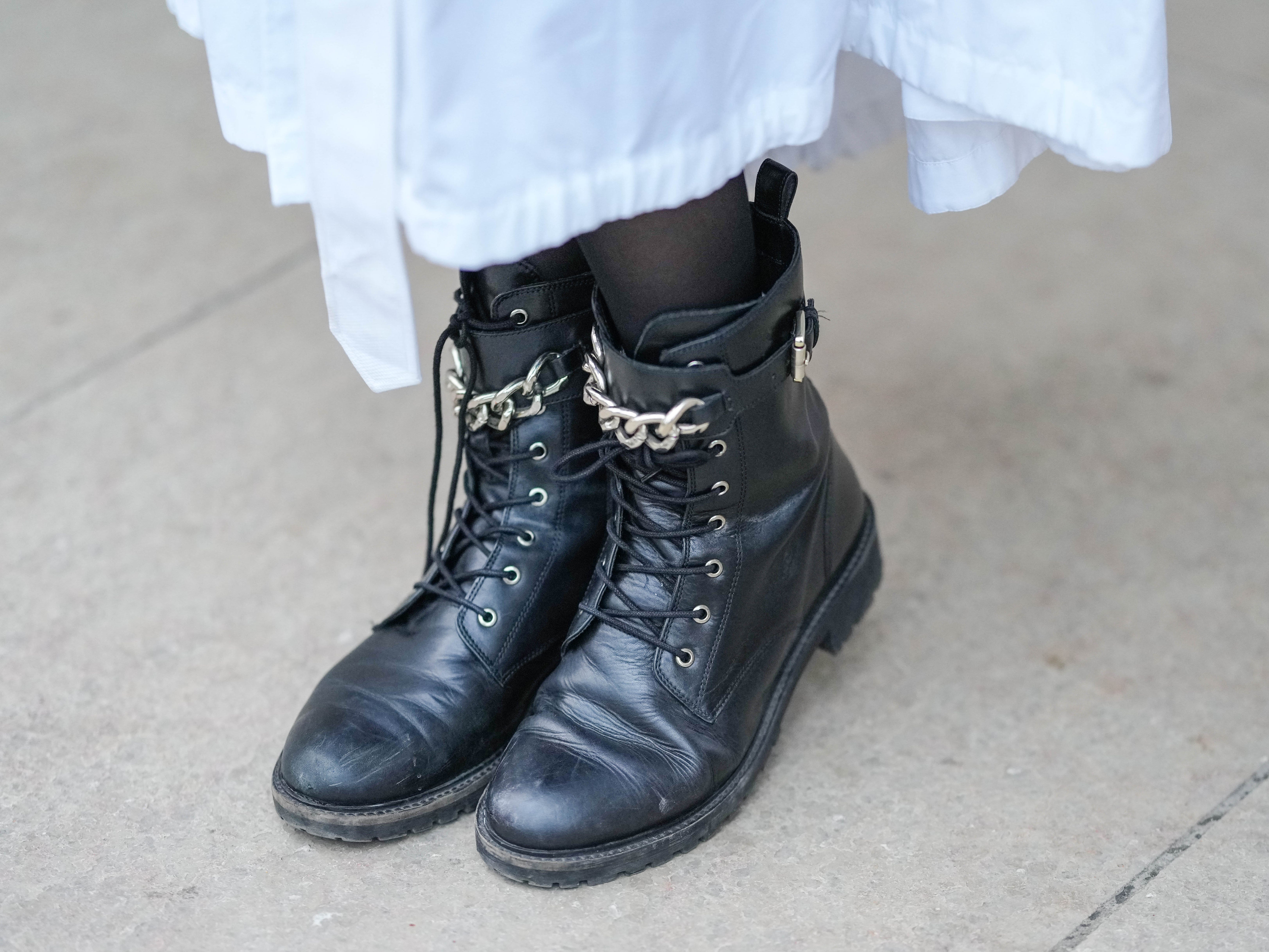 A person wearing a long white skirt and black combat boots.