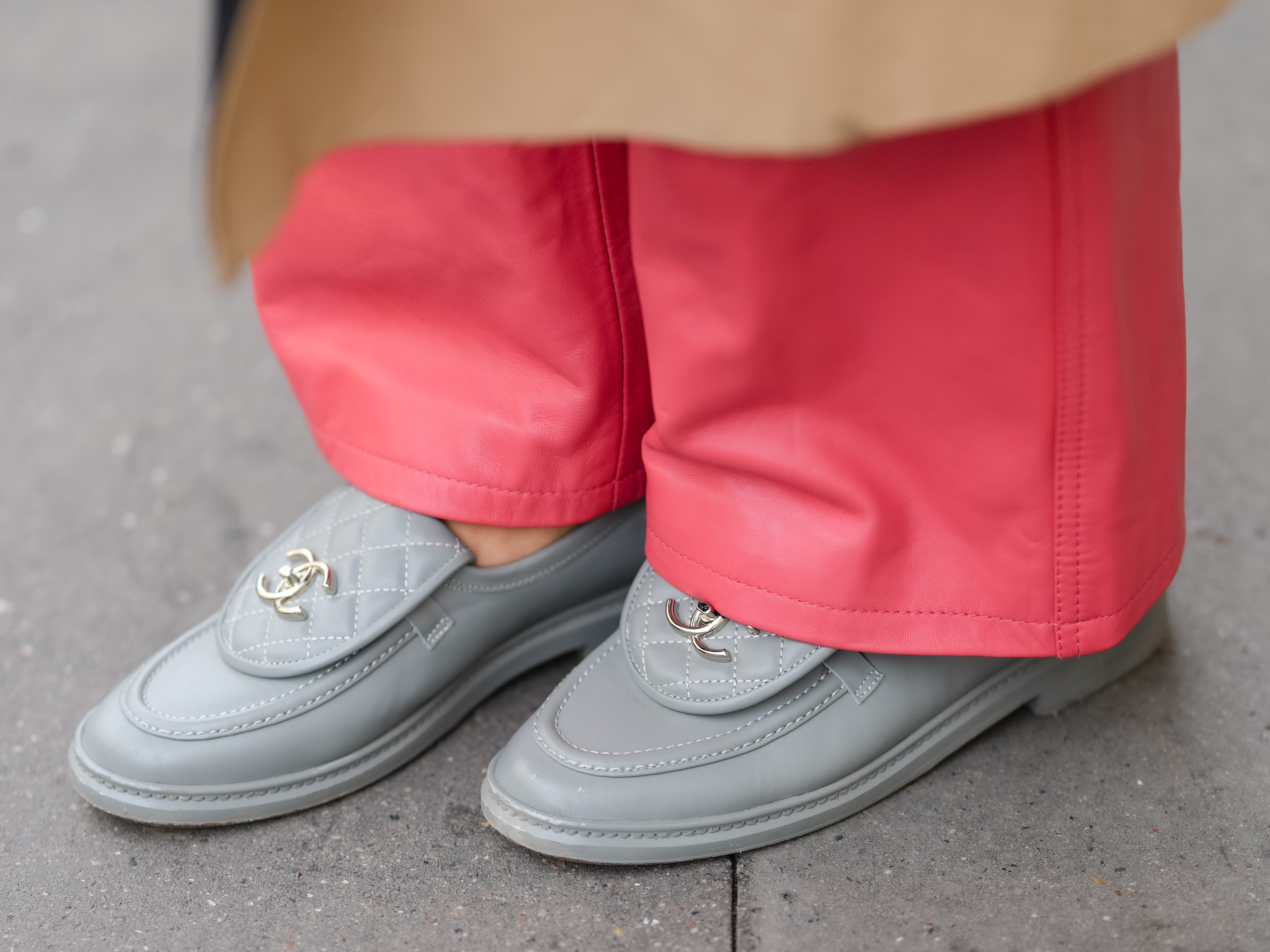 A person wearing pink-leather pants and gray quilted loafers with a Chanel logo on the tongue.