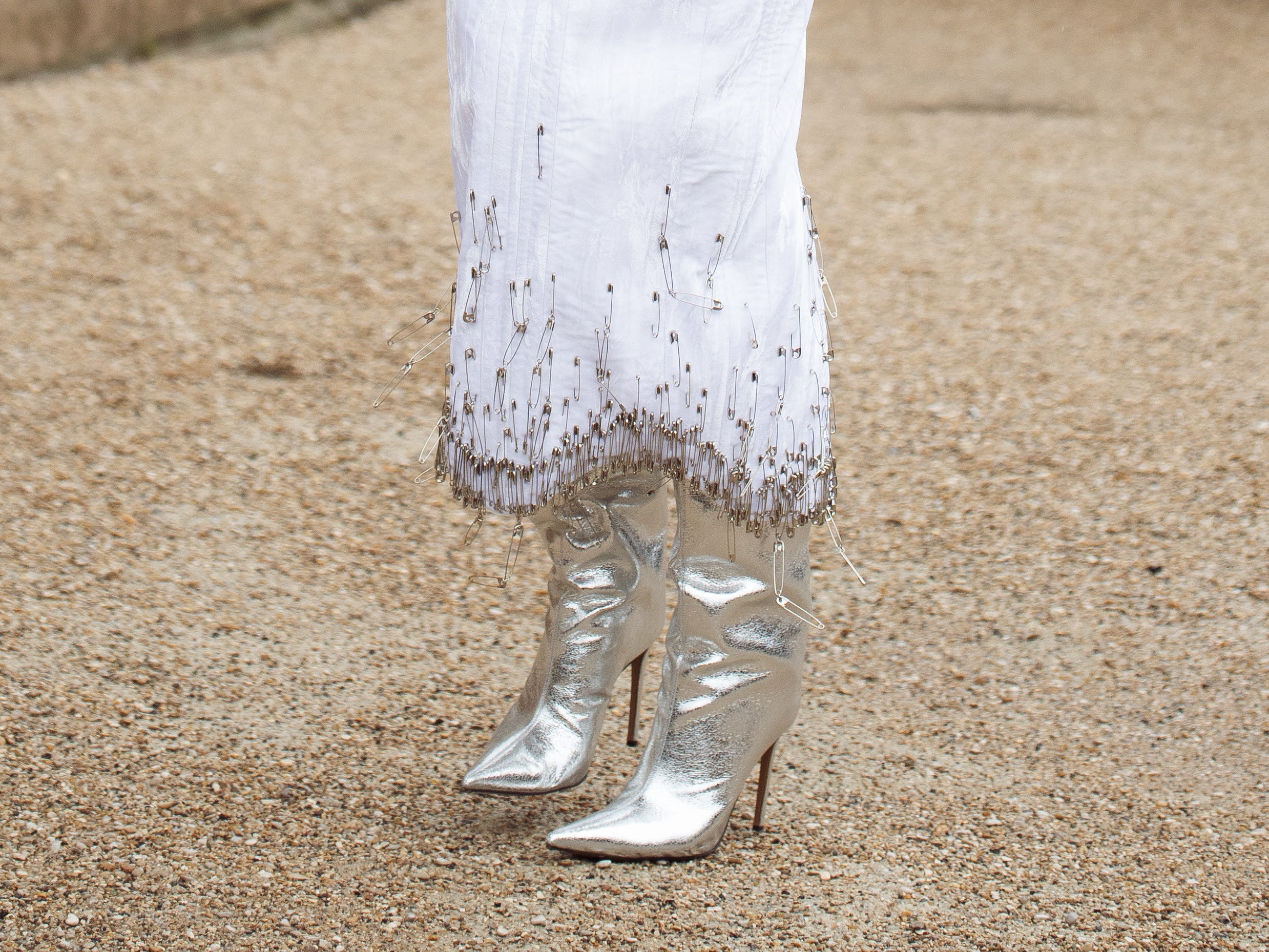 A woman wearing a long dress and metallic silver shoes.