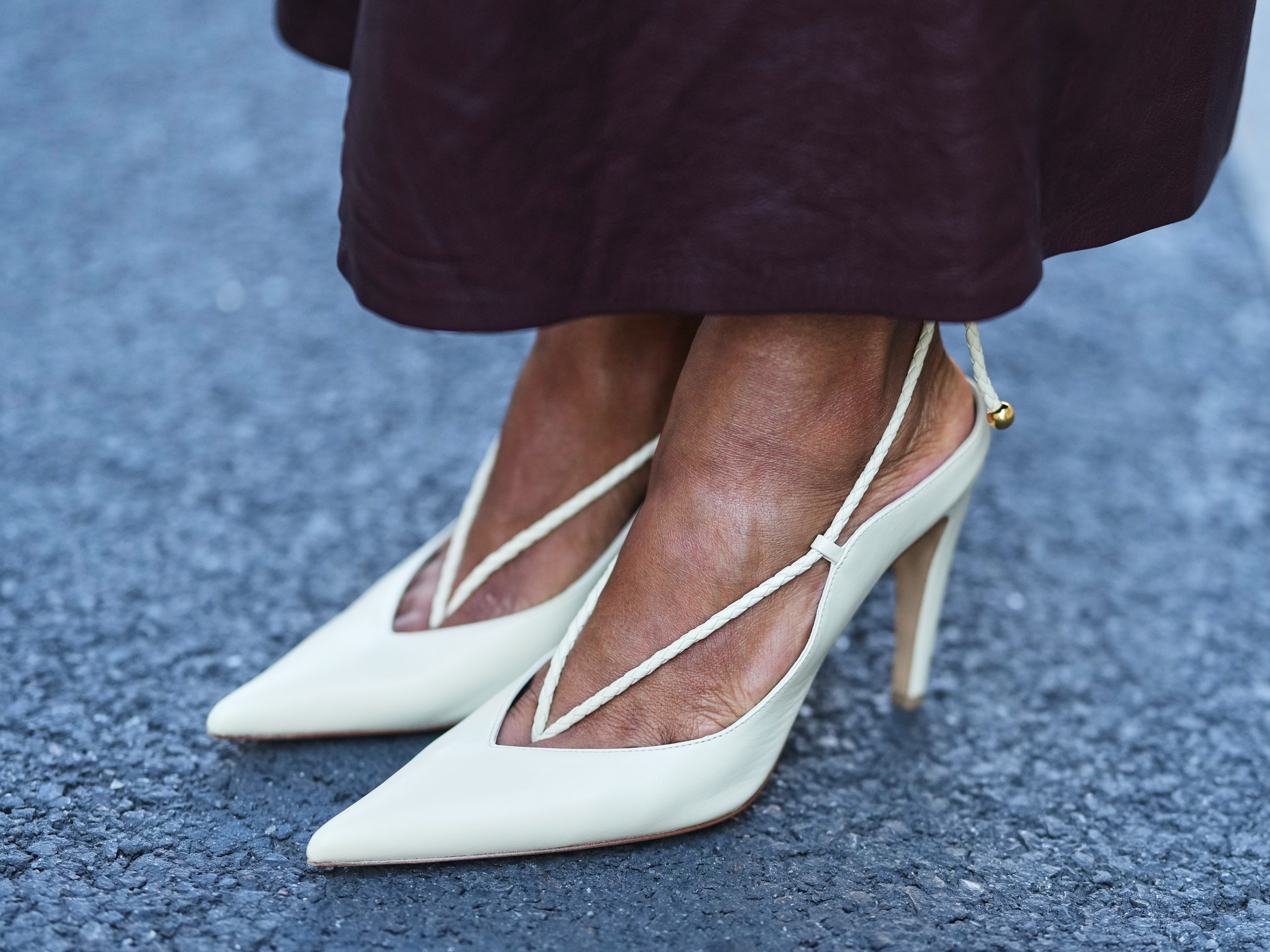 A woman wearing white pointed-toe pumps.