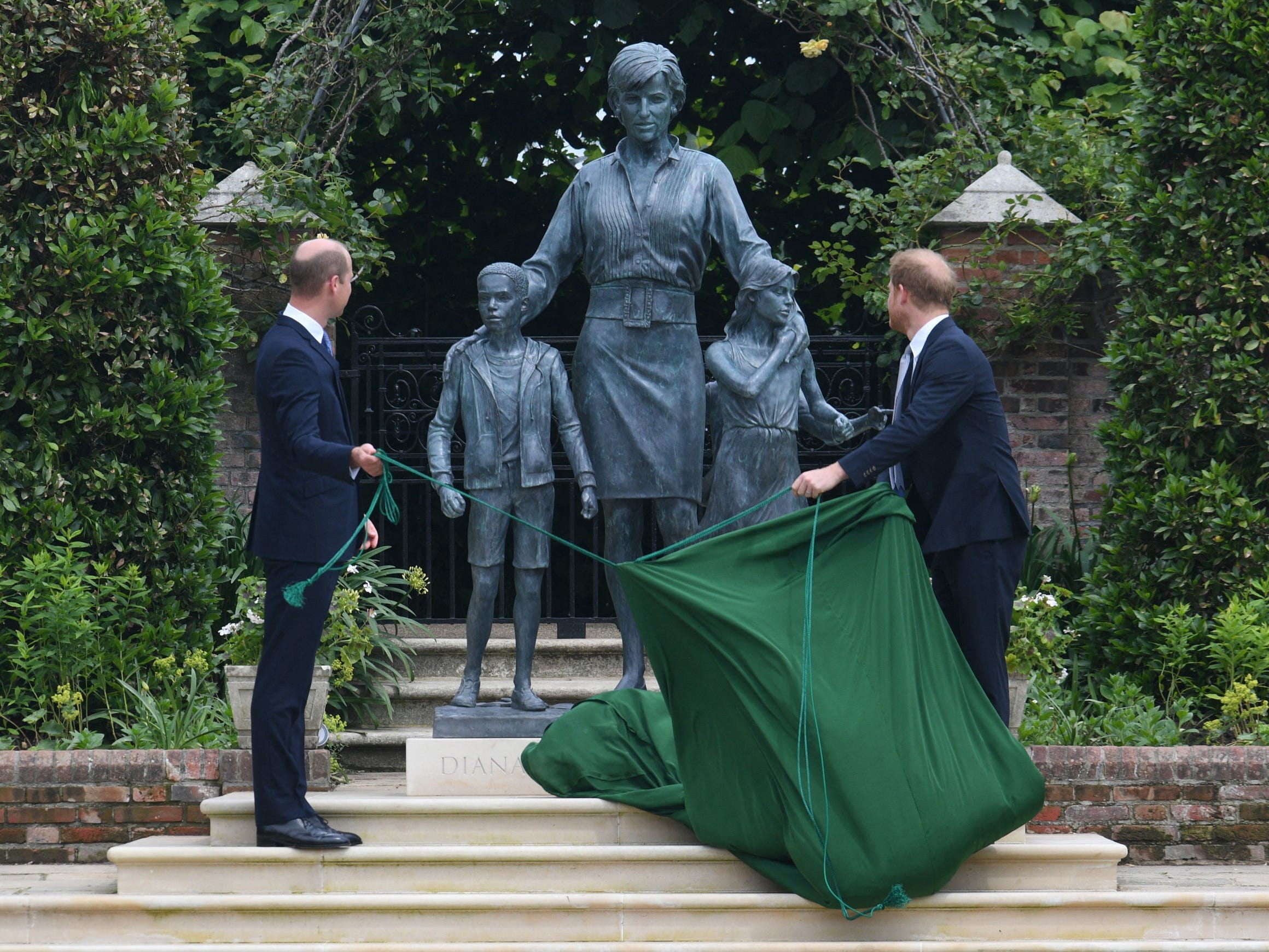 Prince Harry and Prince William pull back a covering to reveal the statue of their mother, Princess Diana, on what would have been her 60th birthday.