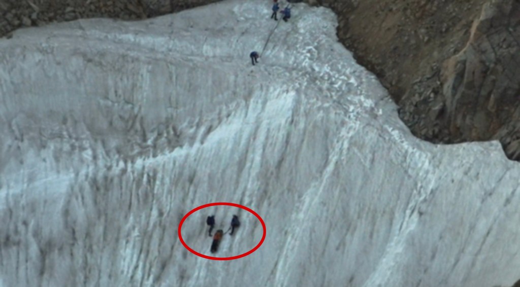 Rescue team assisting a person on a glacier.