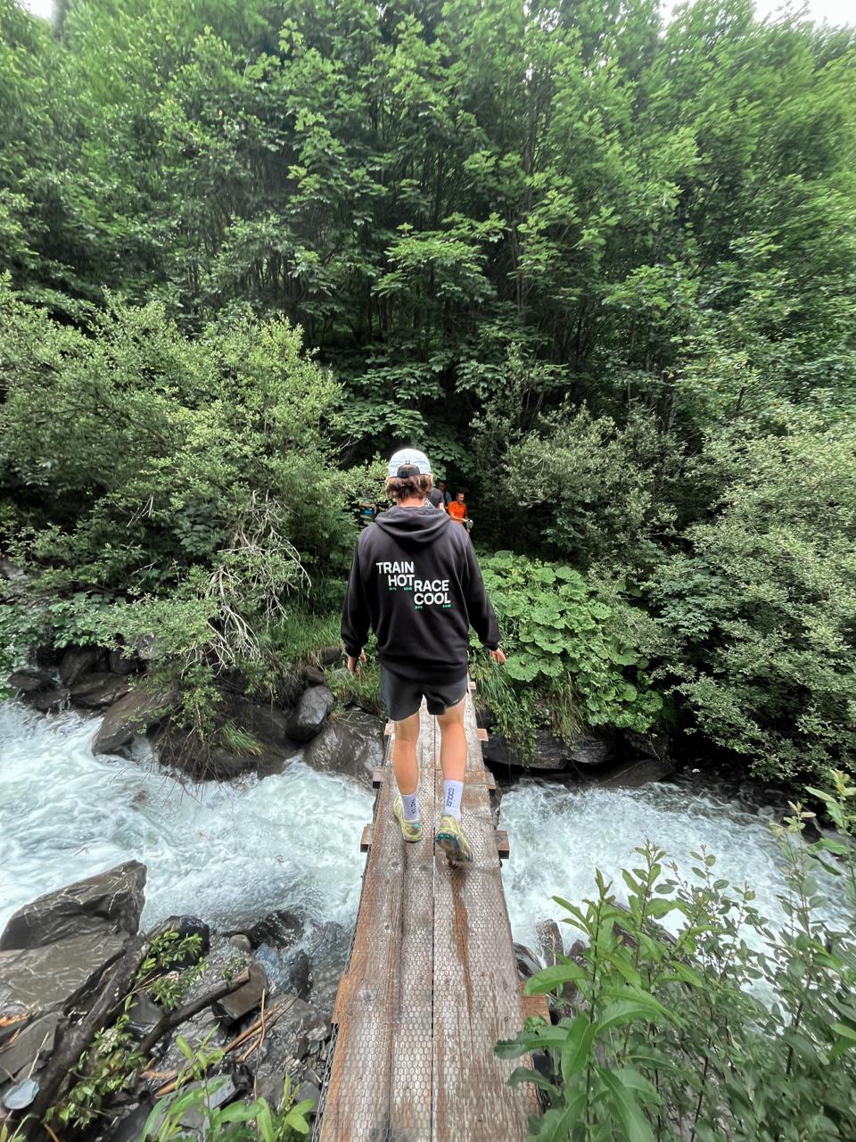 Ross McGraw hiking, walking on a bridge over a body of water.