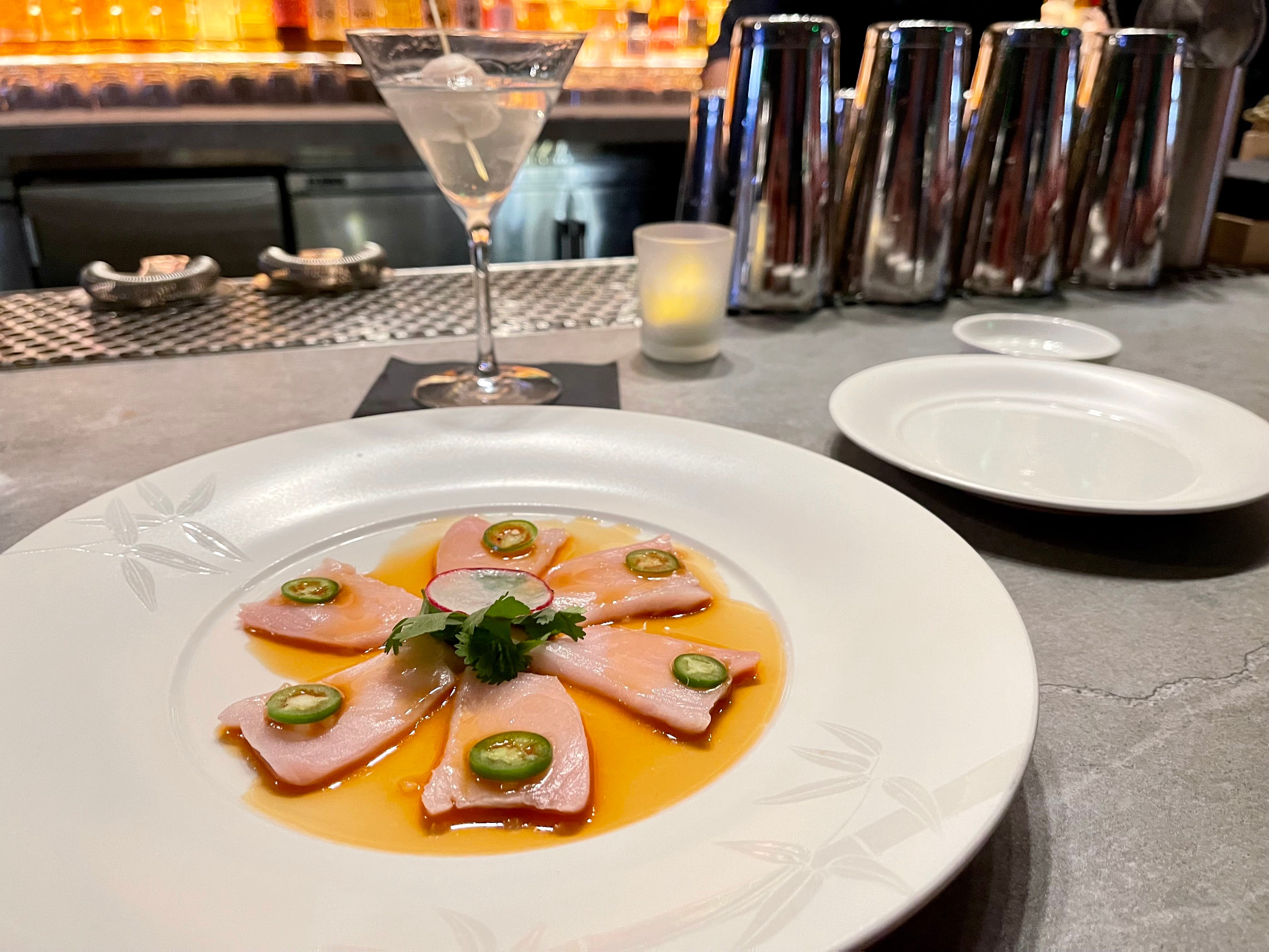 slices of fish in yellow sauce on white round plate at Nobu restaurant