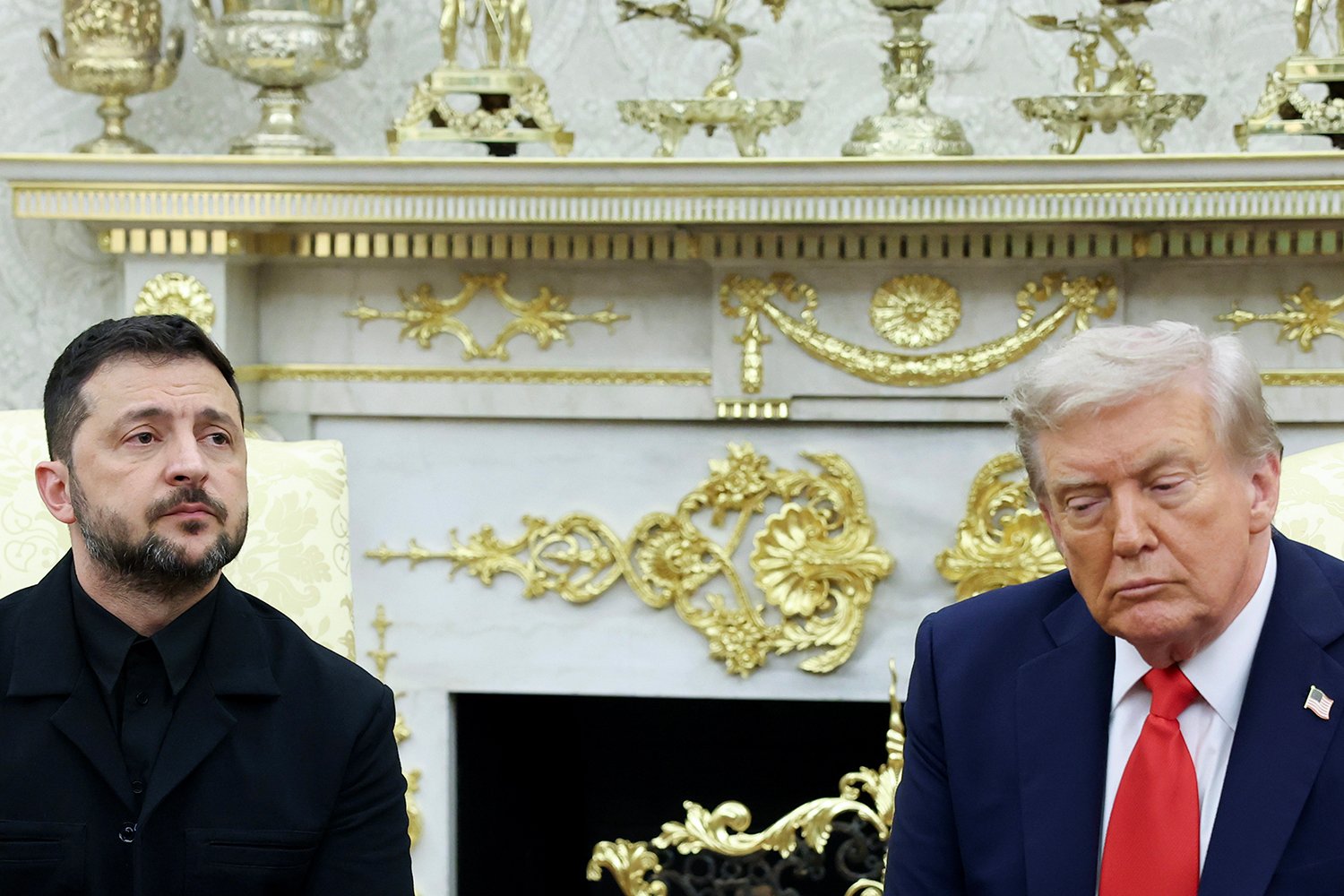 Zelensky and Trump, both seated in front of an ornate gilded mantle, frown.