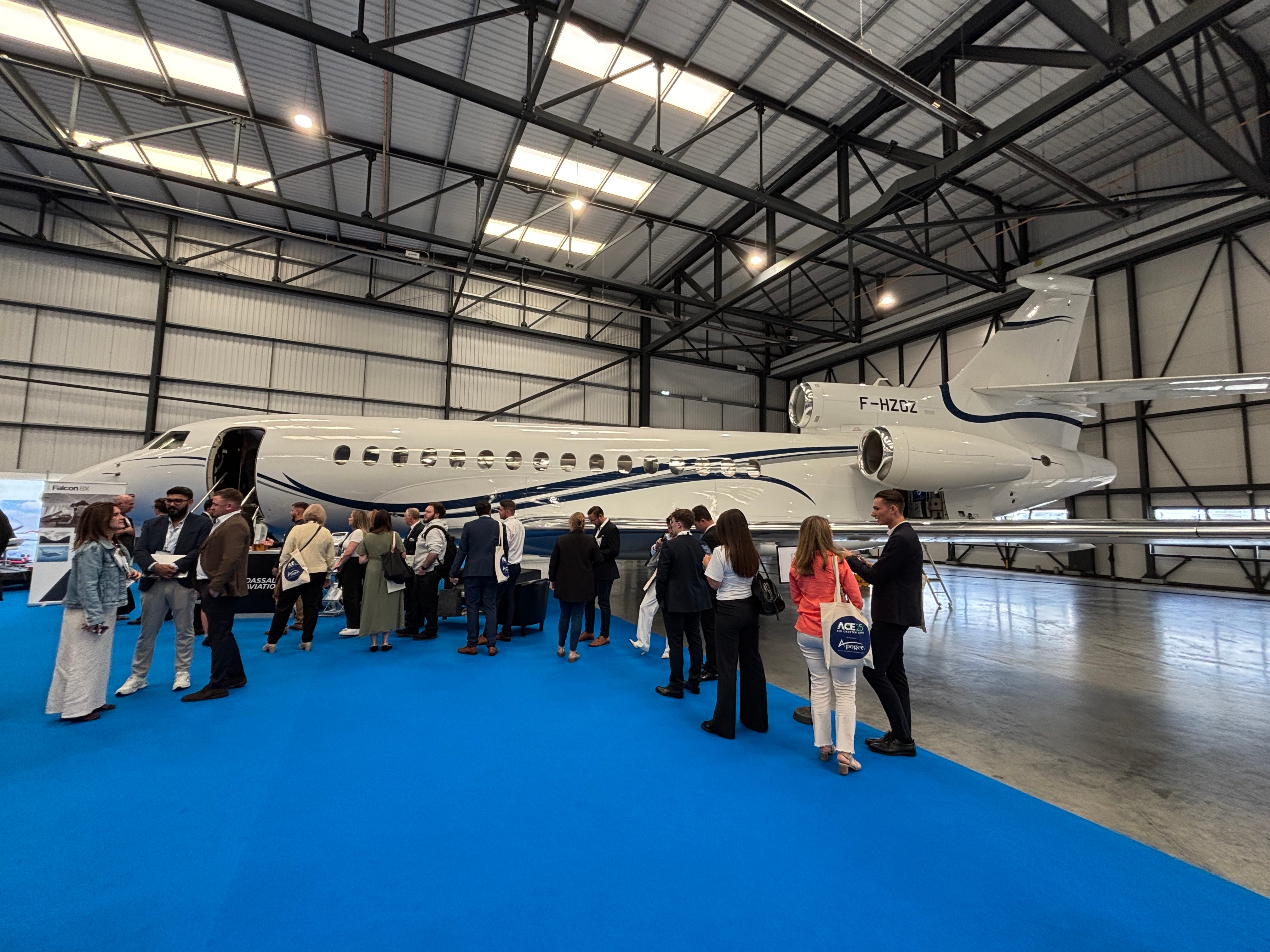 A side view of a Dassault Falcon 8X on display at the 2025 Air Charter Expo with a crowd lining up to tour it