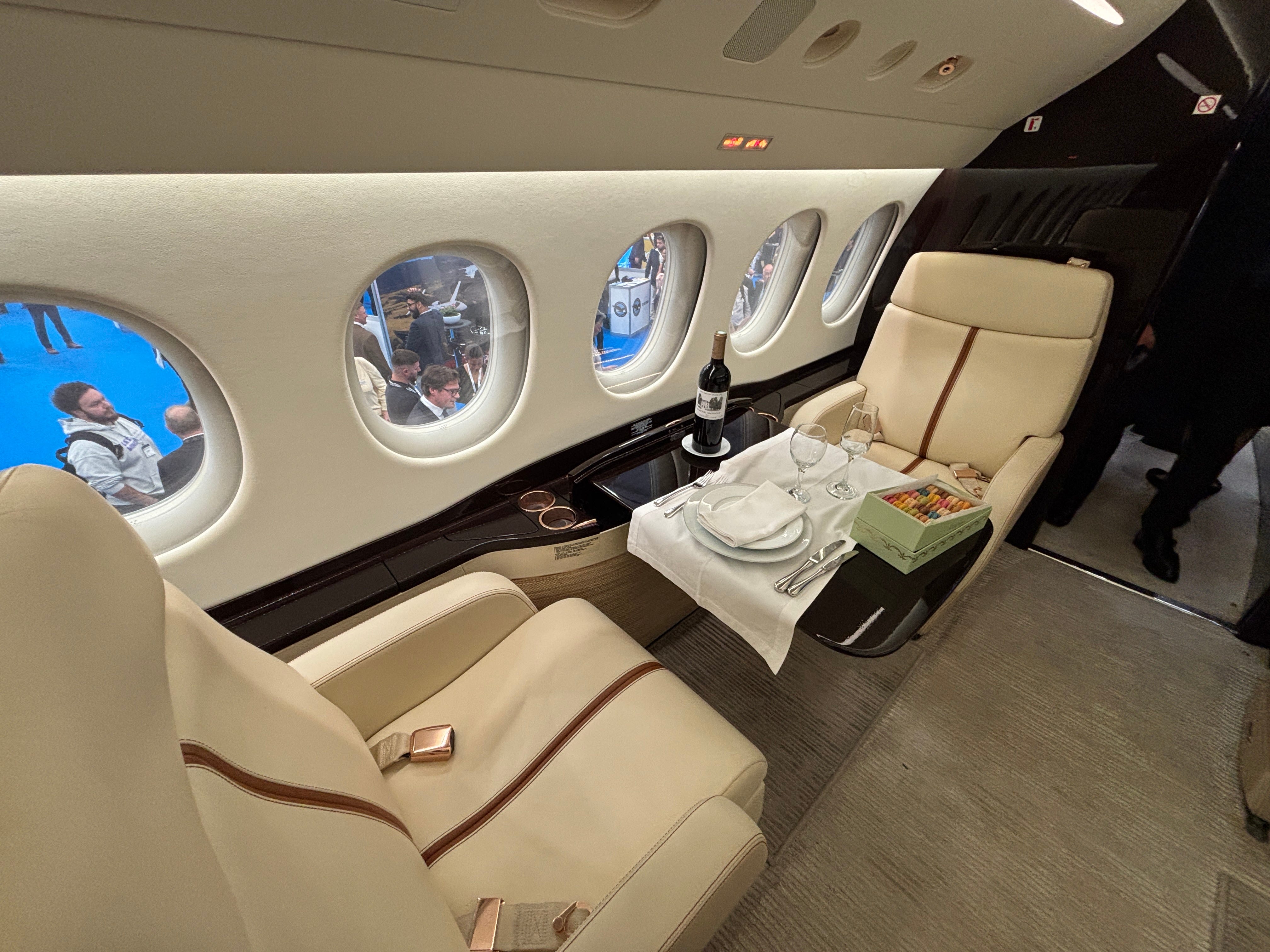 Two seats opposite each other with the table laid for dinner on board a Dassault Falcon 8X on display at the 2025 Air Charter Expo