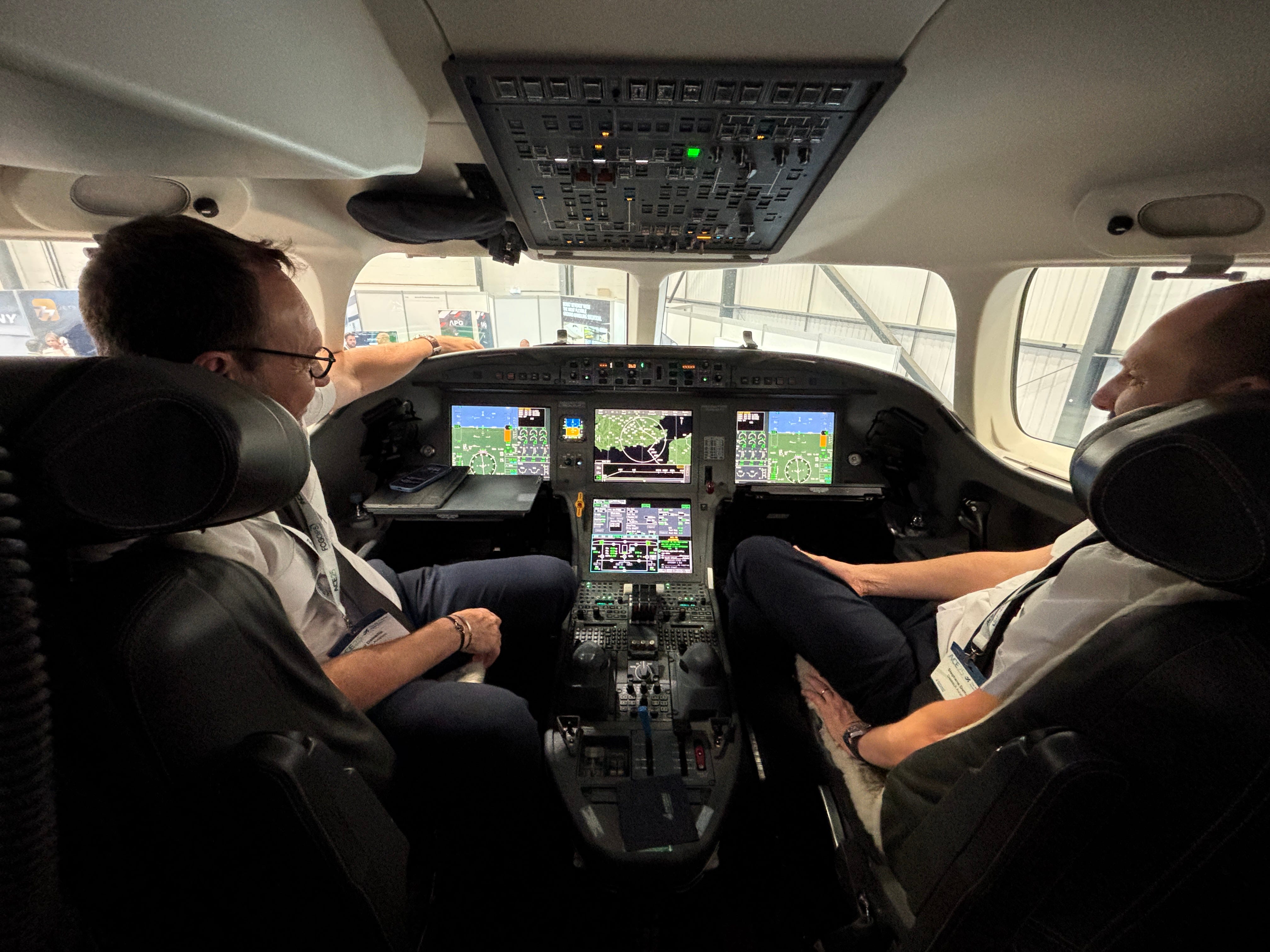Two pilots sit in the flight deck of a Dassault Falcon 8X on display at the 2025 Air Charter Expo
