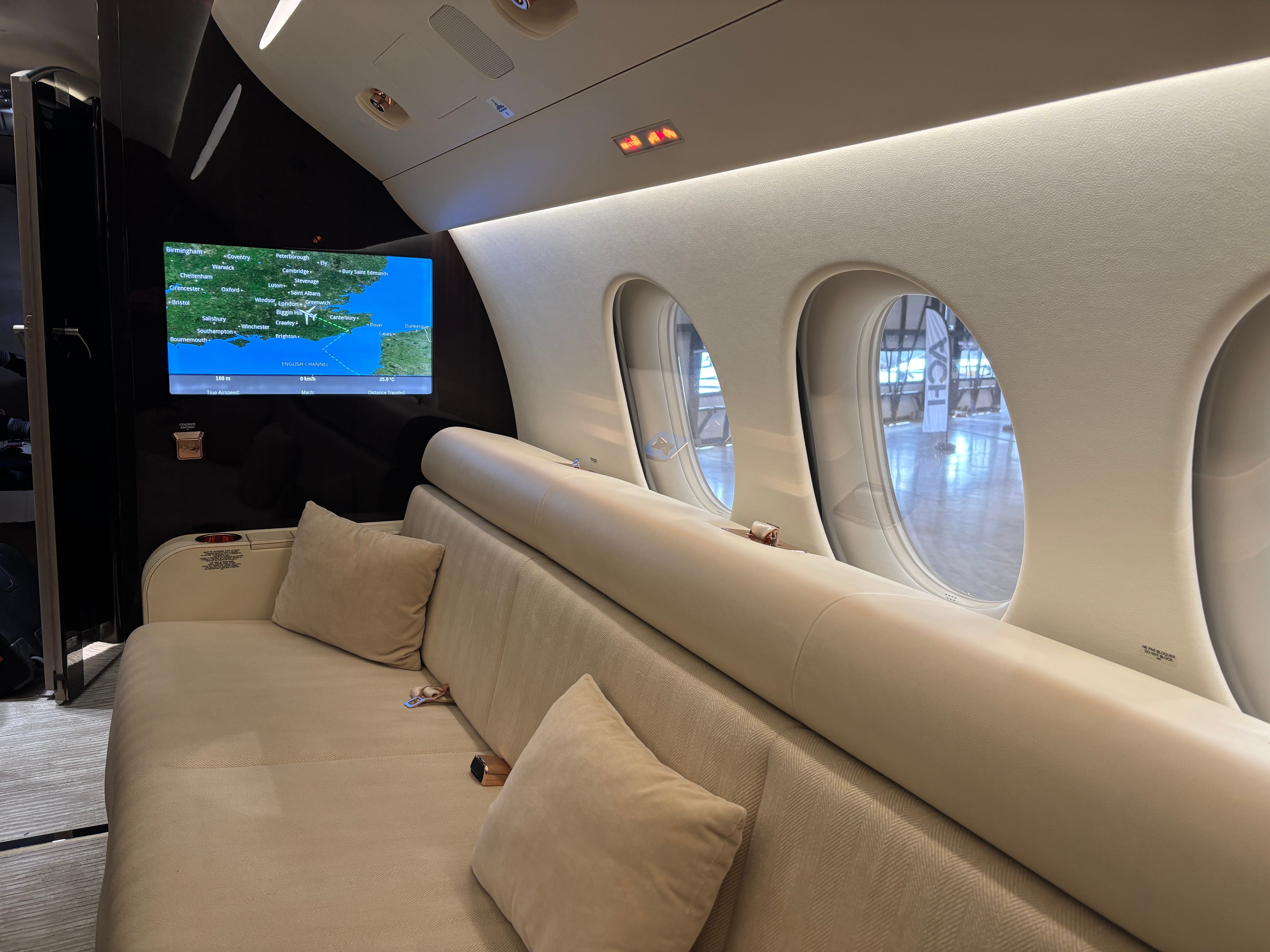A view of the sofa and a map on a TV on board a Dassault Falcon 8X on display at the 2025 Air Charter Expo