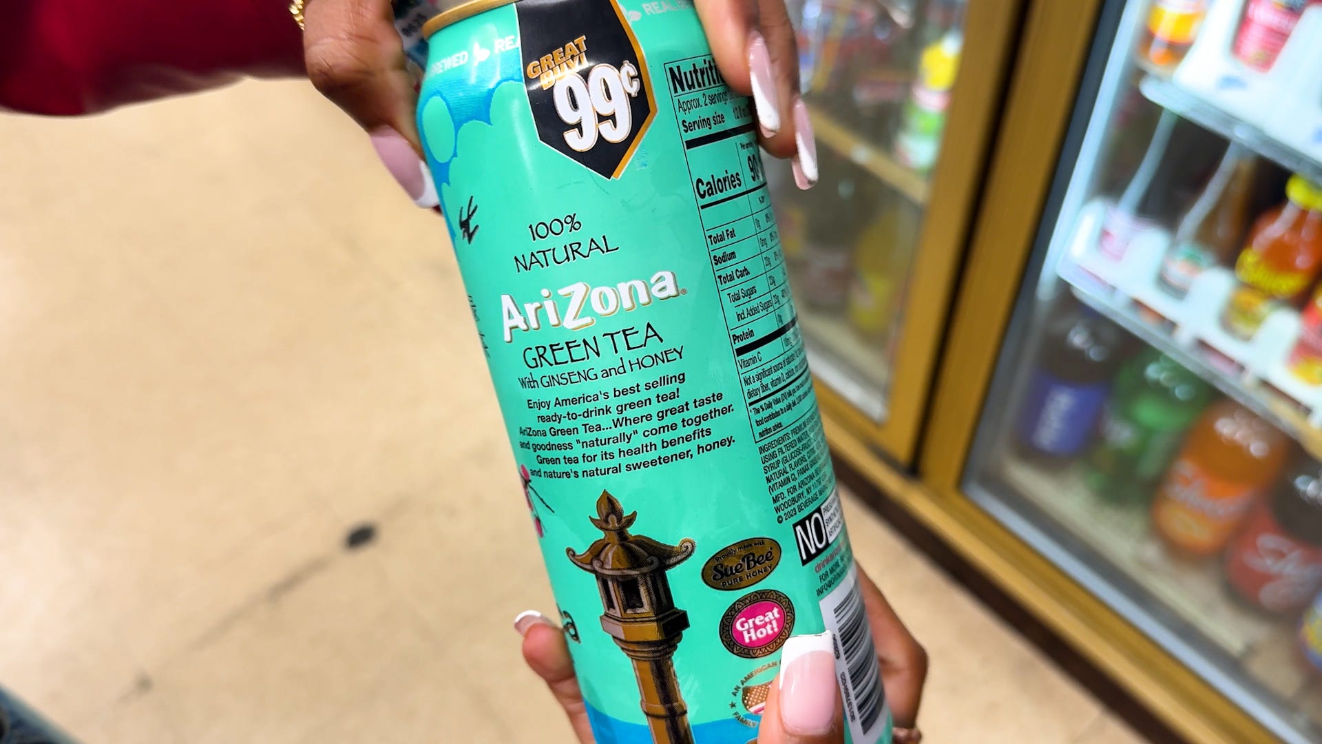 A person holding a blue-green can AriZona green tea.