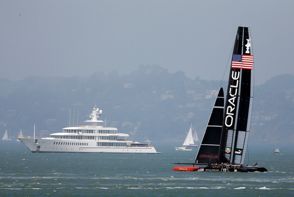 Oracle Team USA catamaran training for the America's Cup, with Larry Ellison's yacht Musashi in the background.