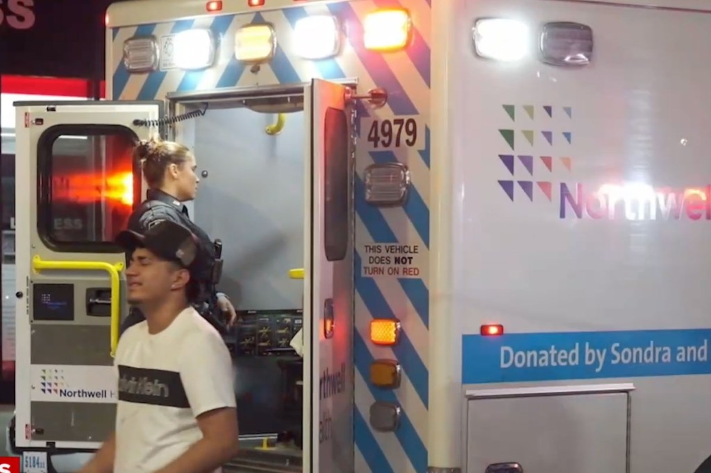 Police officer and suspect near ambulance.