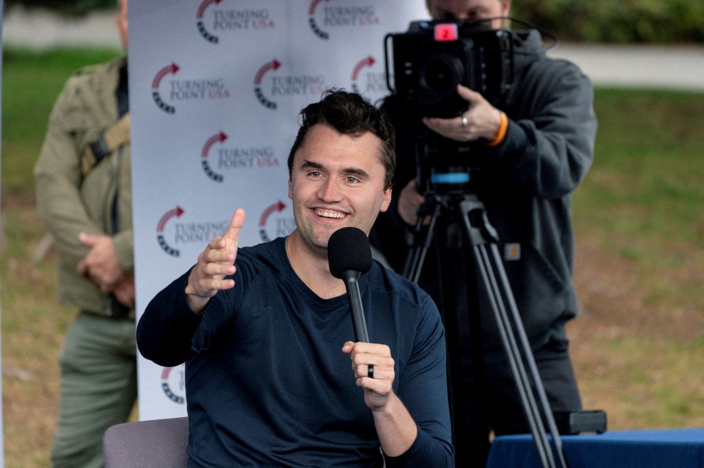 Charlie Kirk speaking into a microphone at a Turning Point USA event.