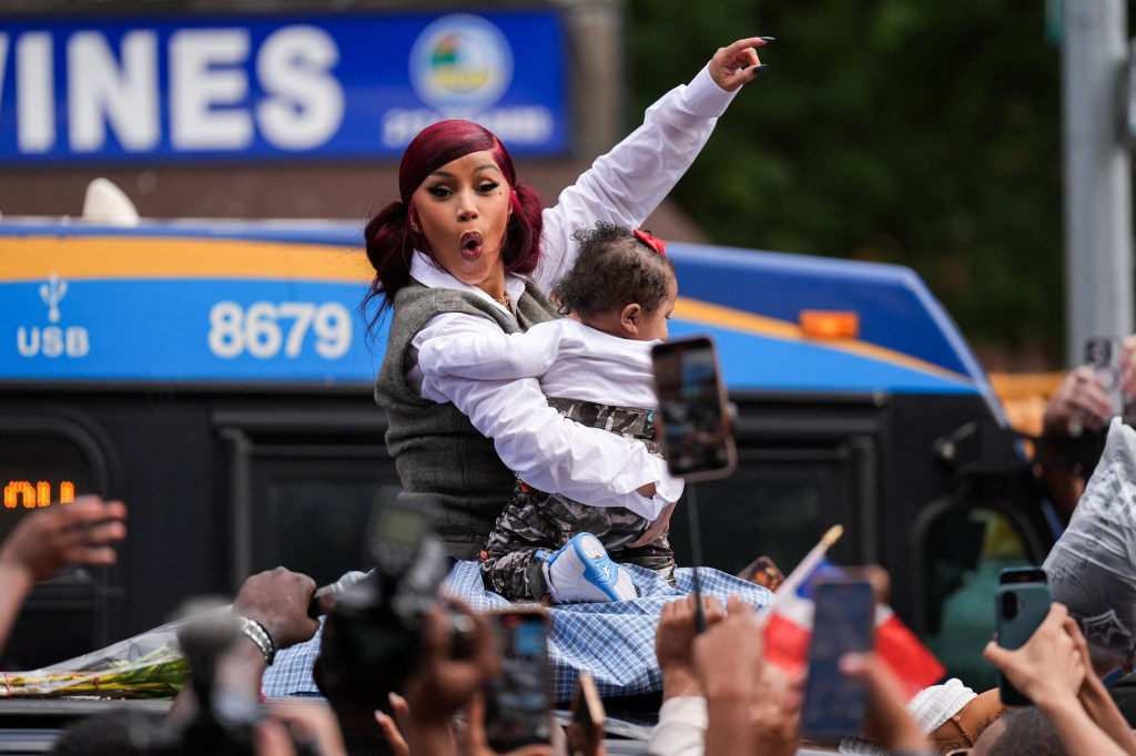 Cardi B holding a baby at a pop-up event.