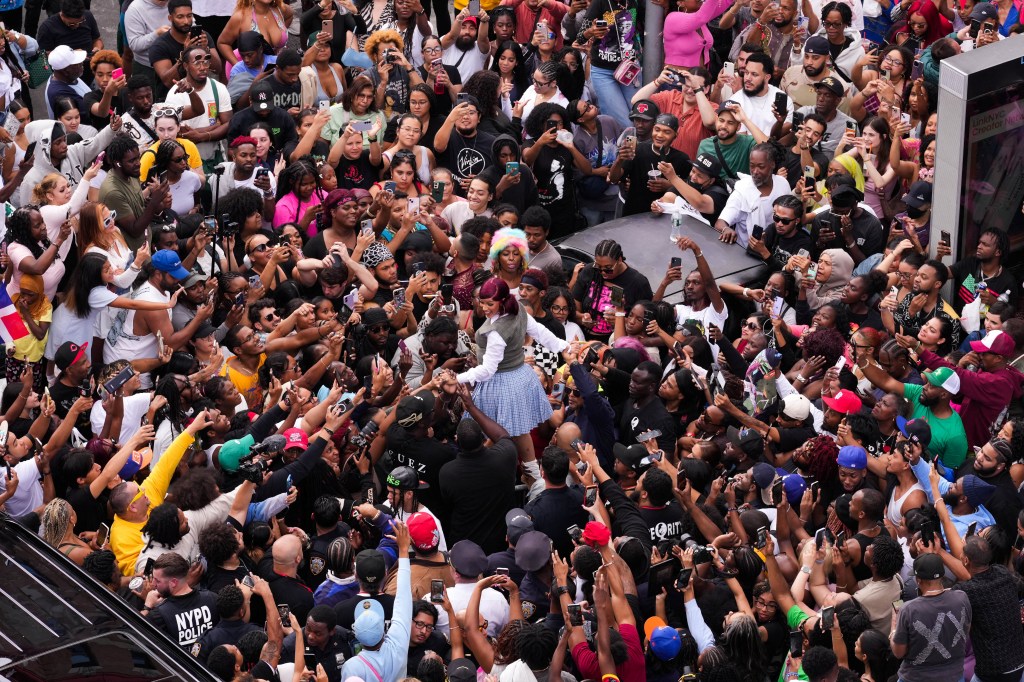 Cardi B at a pop-up bodega event, surrounded by a large crowd.