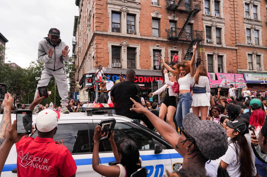 Cardi B performing on top of an NYPD vehicle at a pop-up event.