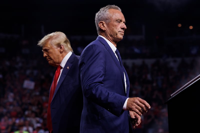 Robert F. Kennedy Jr. walks past Republican presidential nominee Donald Trump during a campaign event at the Desert Diamond Arena in Glendale, Arizona, on August 23, 2024. Kennedy announced the suspension of his presidential campaign and said he would endorse Trump.