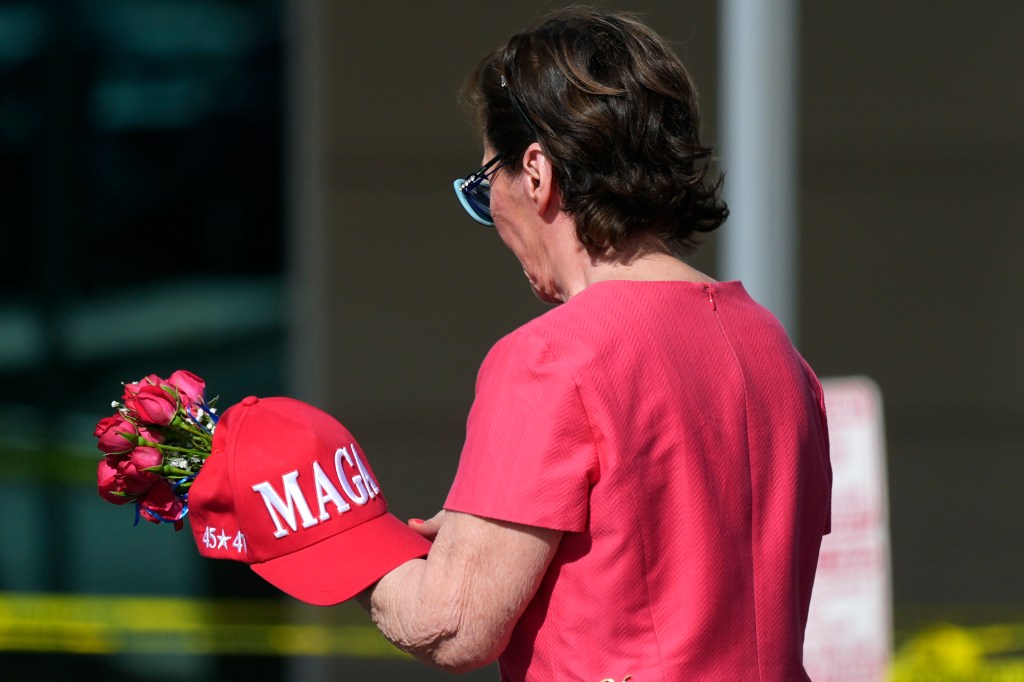 Woman holding a MAGA hat with roses.