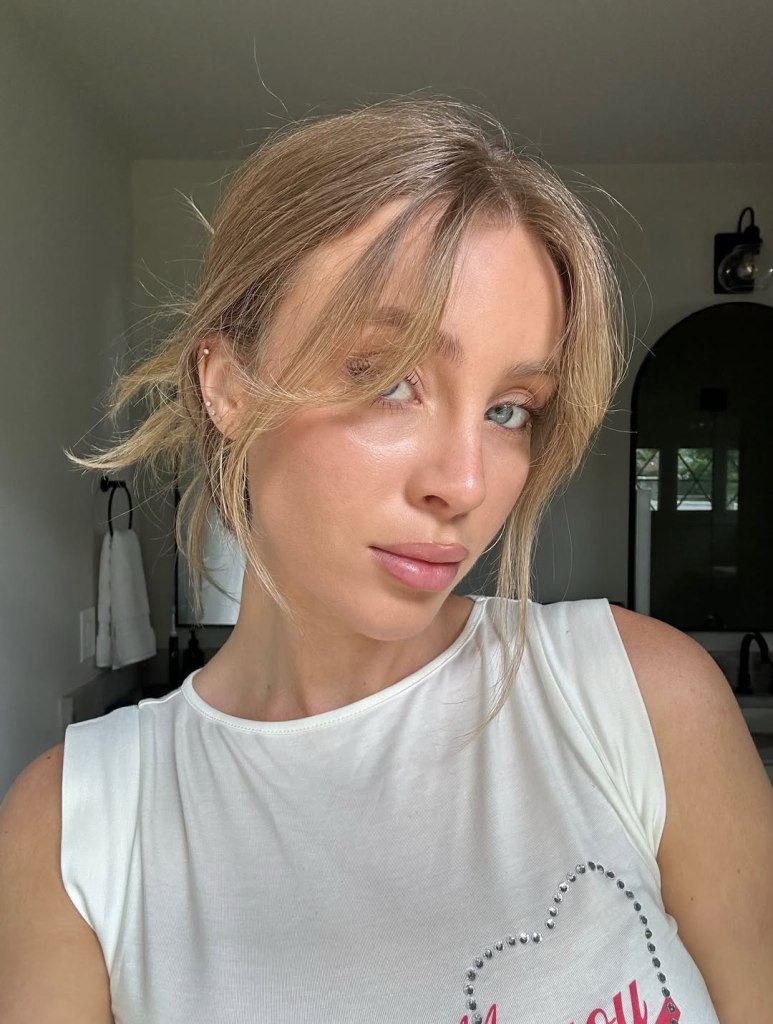 Woman with blonde hair and bangs wearing a white tank top.