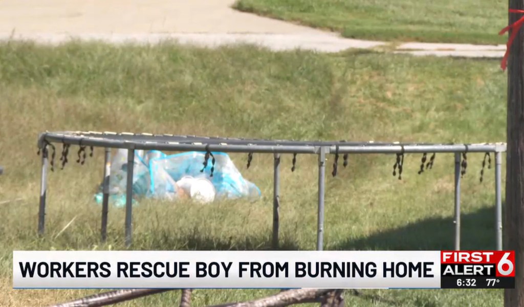 Workers rescuing a boy from a burning home.