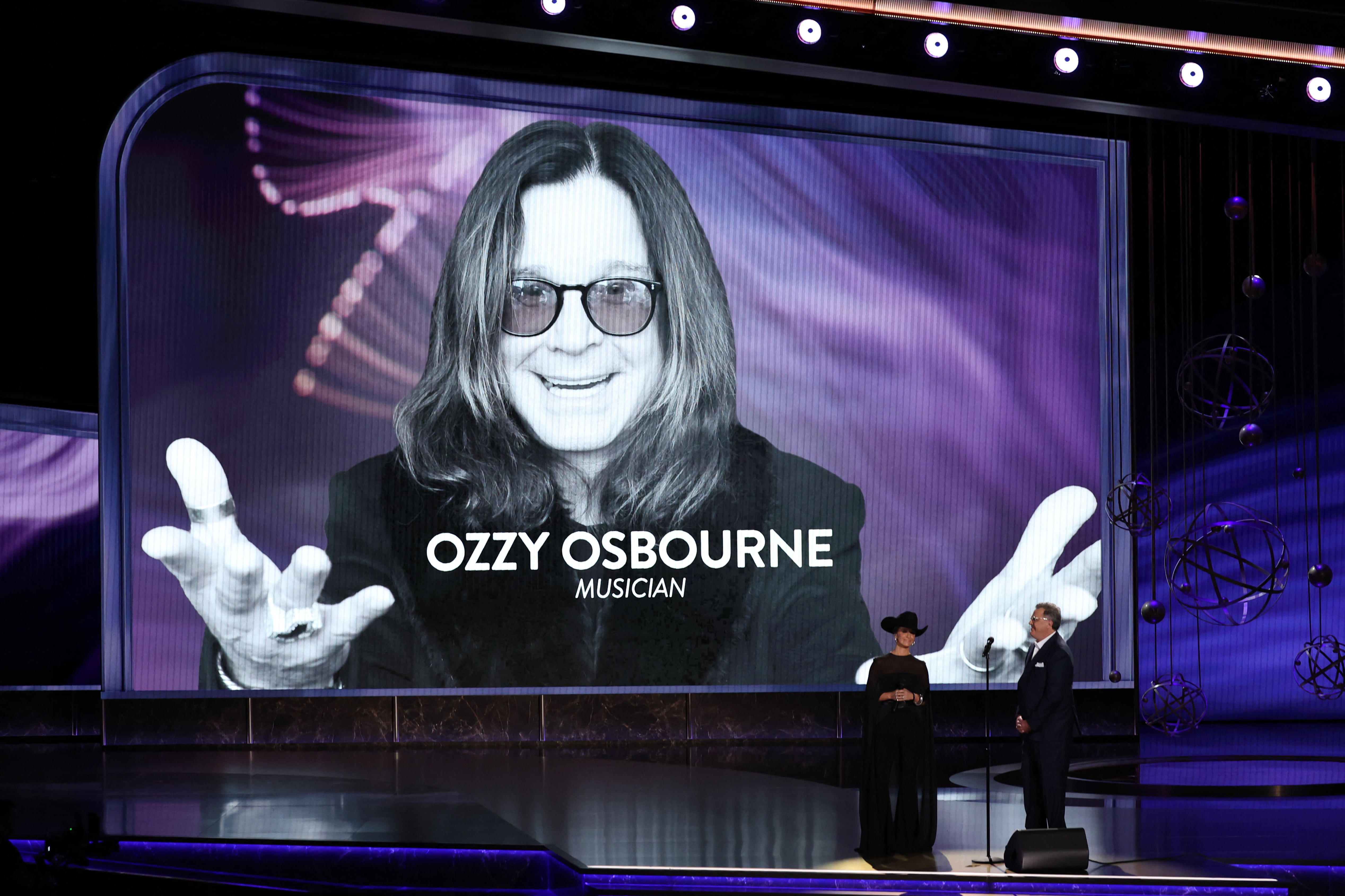 A picture of Ozzy Osbourne is seen on screen as US singer-songwriters Vince Gill and Lainey Wilson perform onstage during the 77th Primetime Emmy Awards at the Peacock Theatre at LA Live in Los Angeles on September 14, 2025.