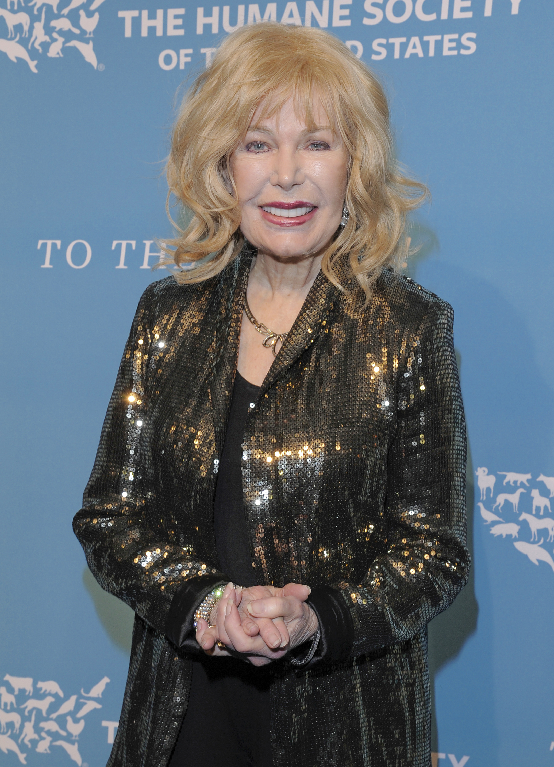 Loretta Swit in a gold jacket at an event. 