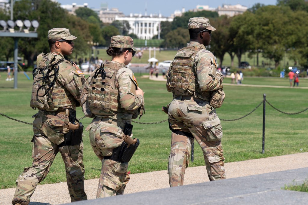 Ohio National Guard members patrol the National Mall with the White House in the background.
