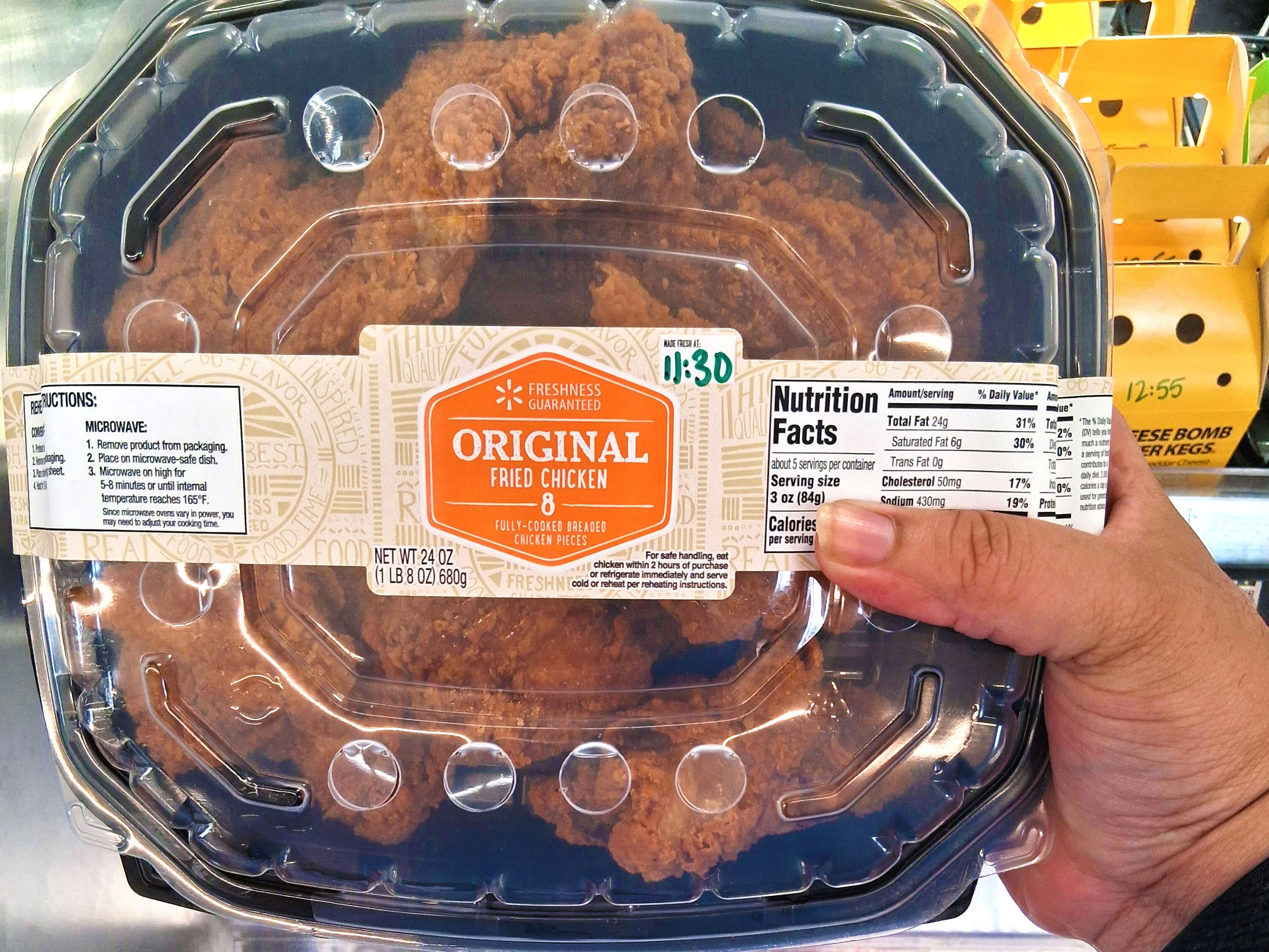 A hand holding a container of Walmart's original fried chicken.