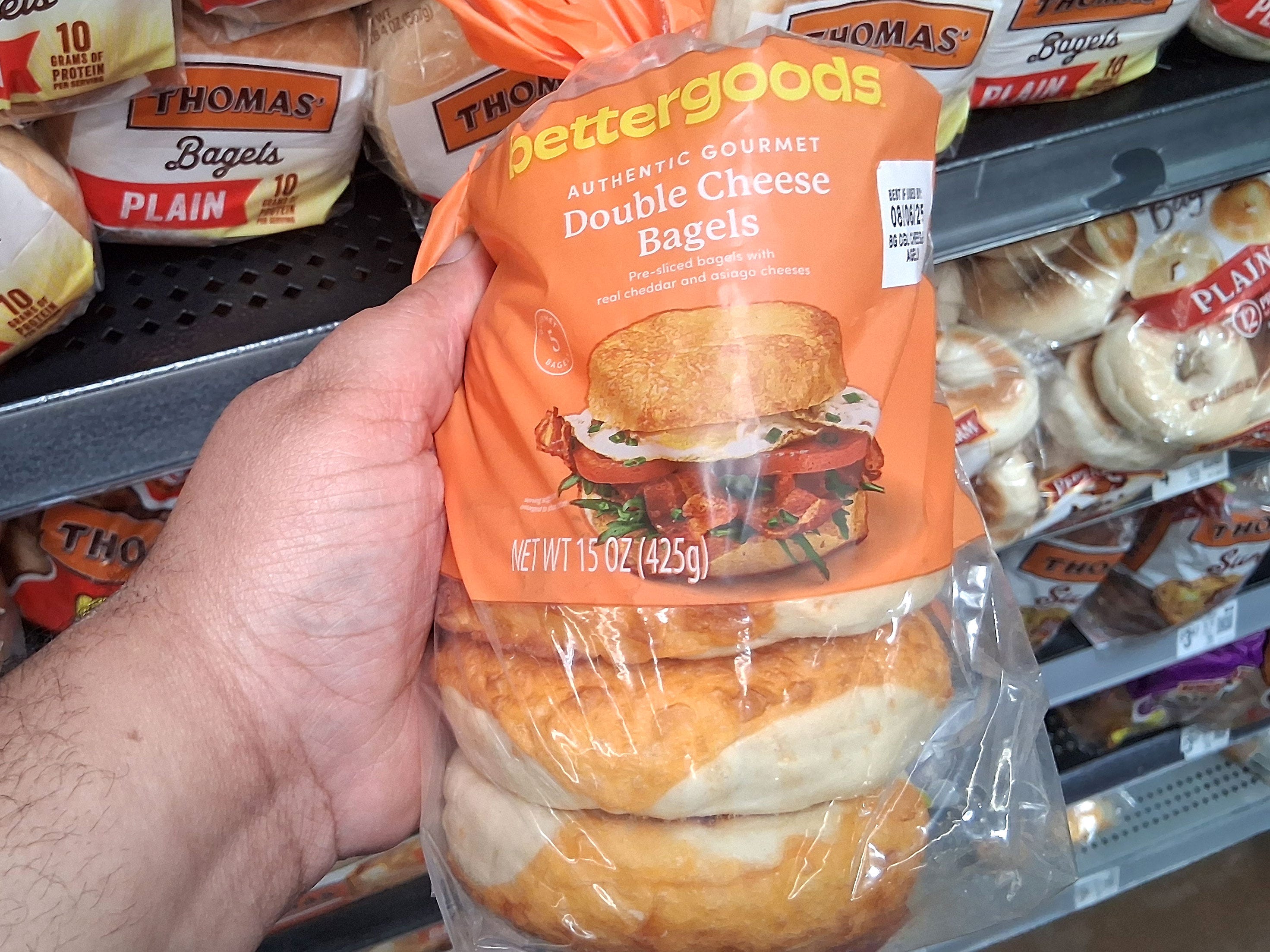 A hand holding a bag of Bettergoods double-cheese bagels.