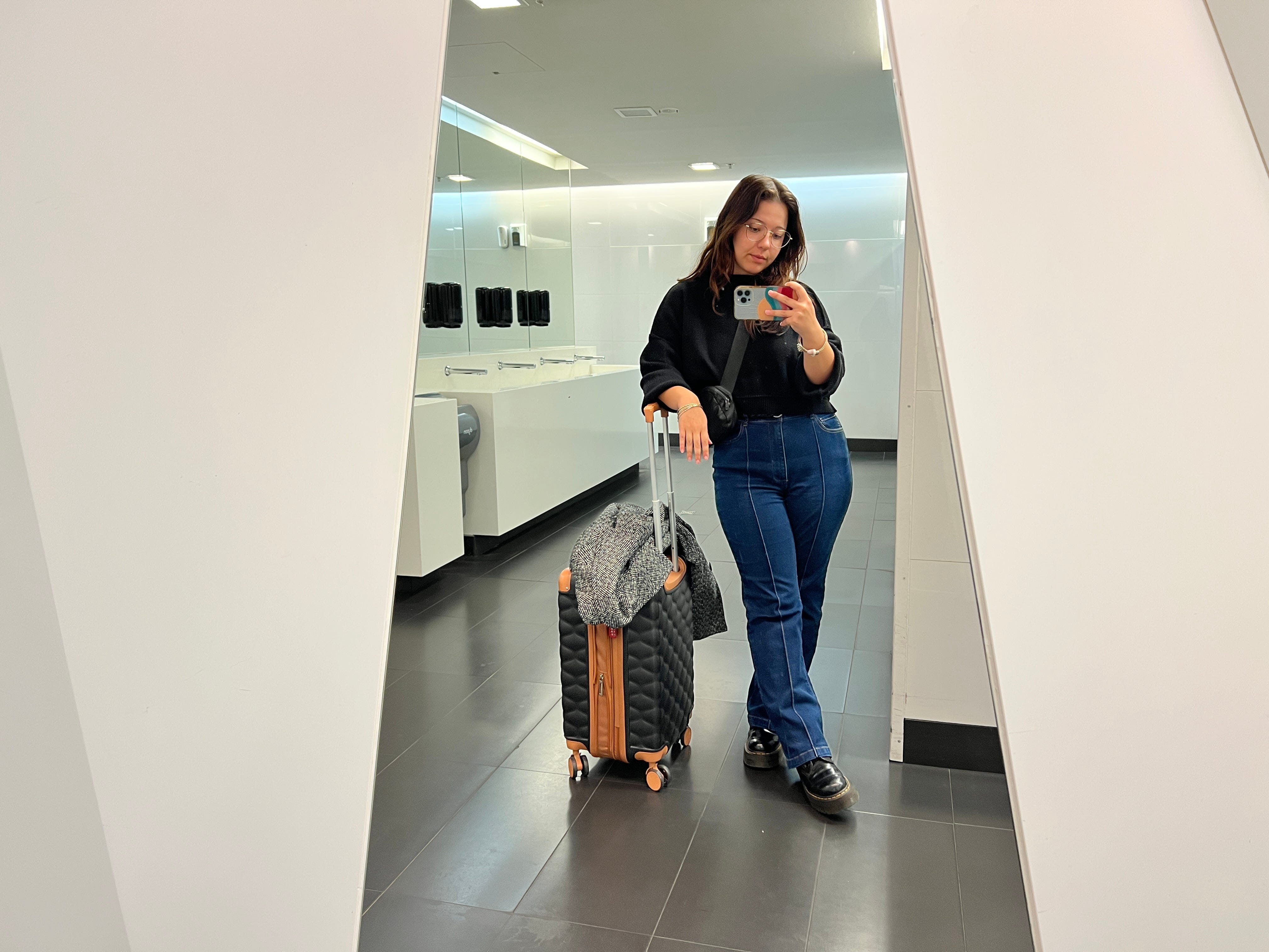 The author posing in a mirror with her carry-on suitcase.