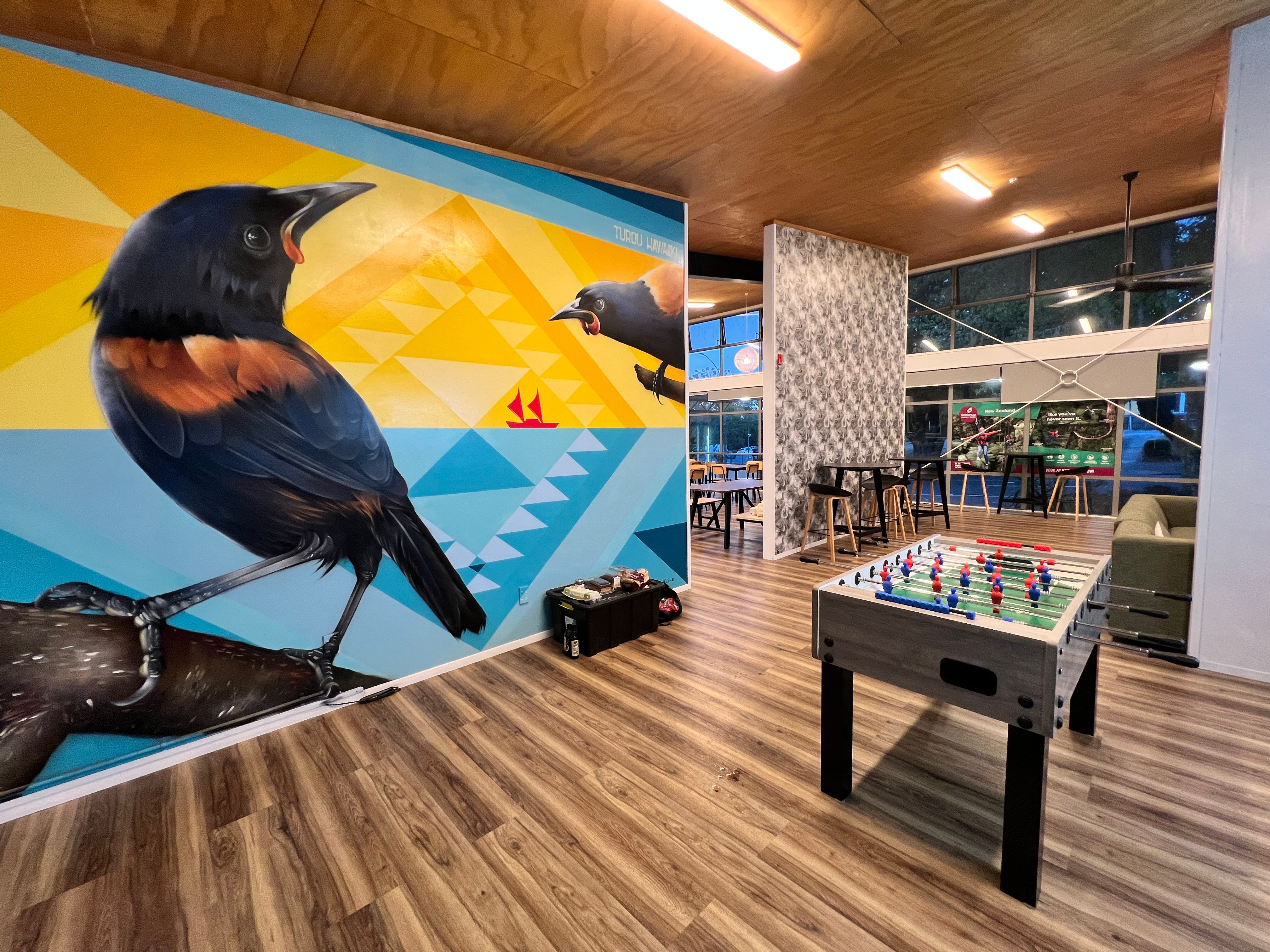 A foosball table at a hostel in Rotorua, New Zealand. The wall has a mural with two birds.