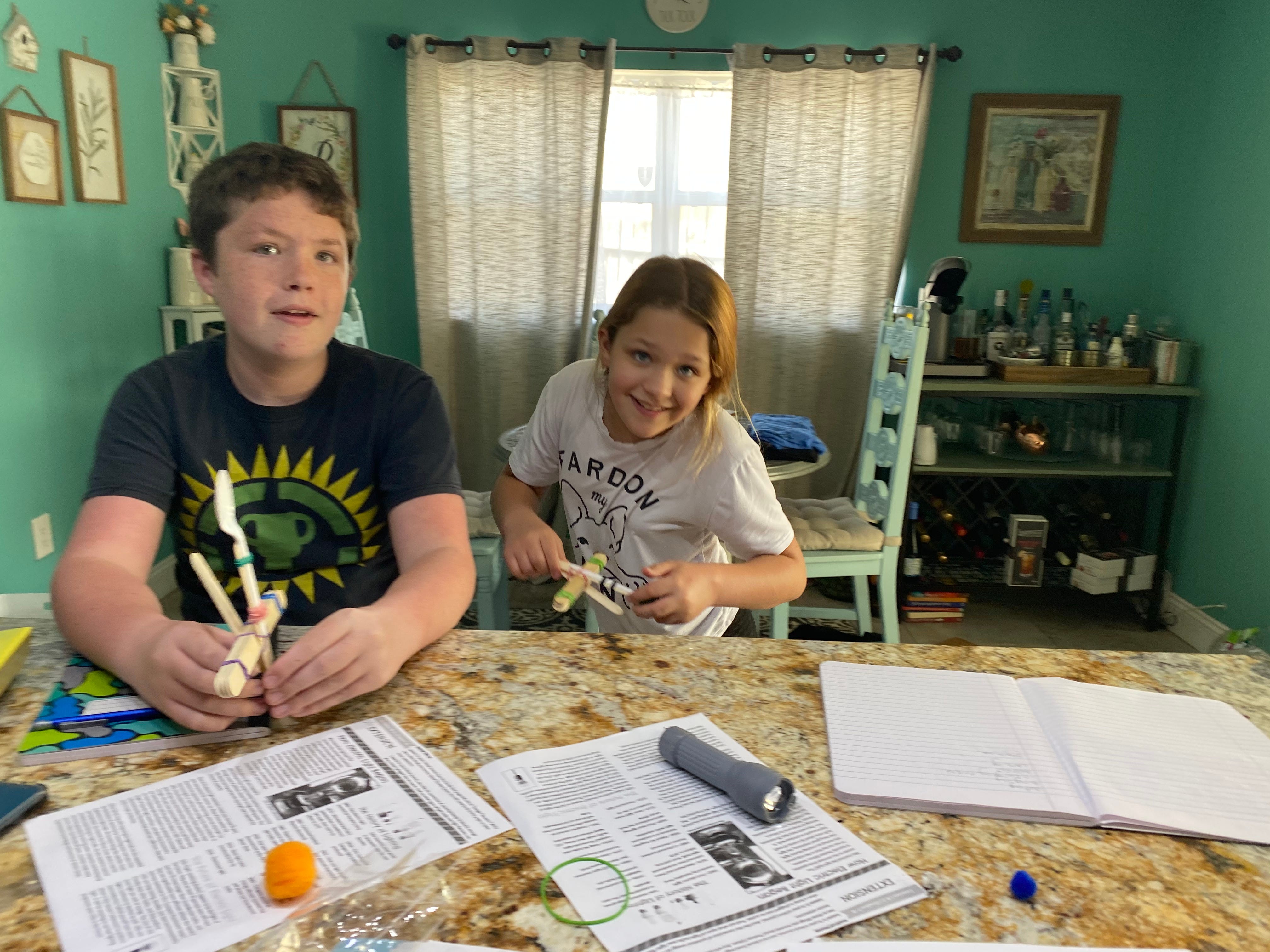 The author's kids doing homeschooling activities at the dining room table.