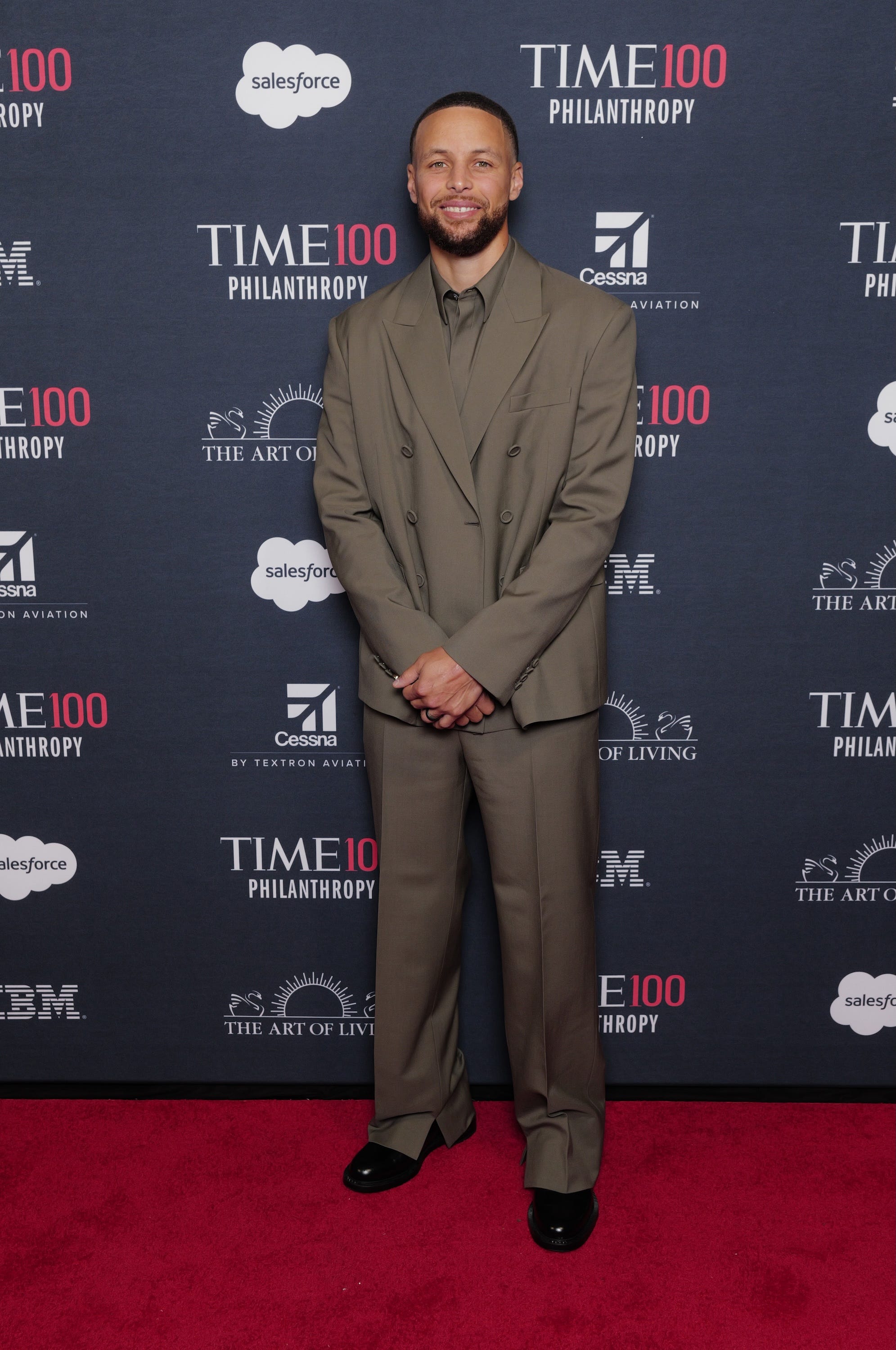 Stephen Curry poses for photographers on the TIME100 red carpet in New York City while wearing a brown suit.