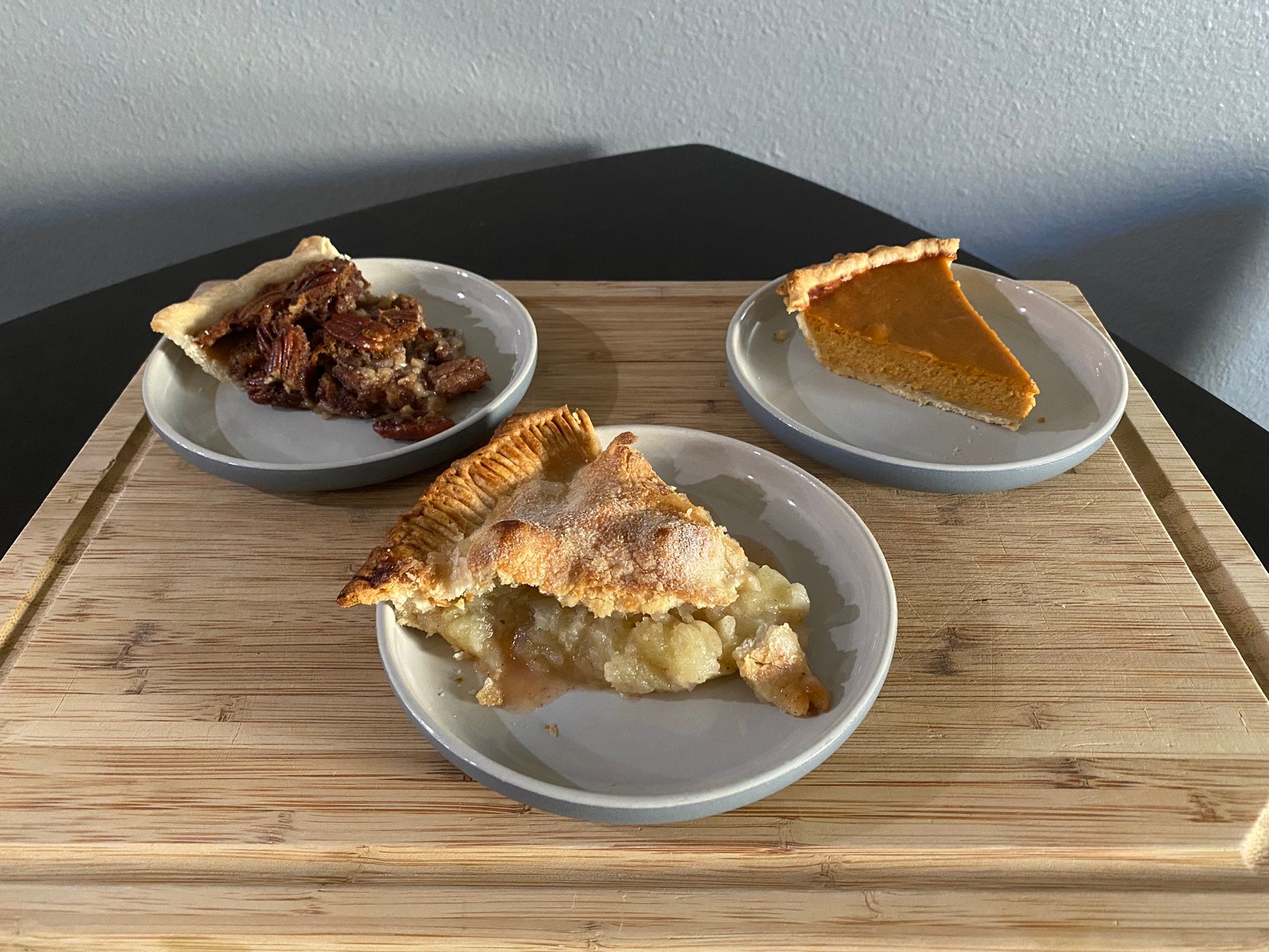 slice of pecan pie on a plate, slice of apple pie on a plate, and slice of pumpkin pie on a plate